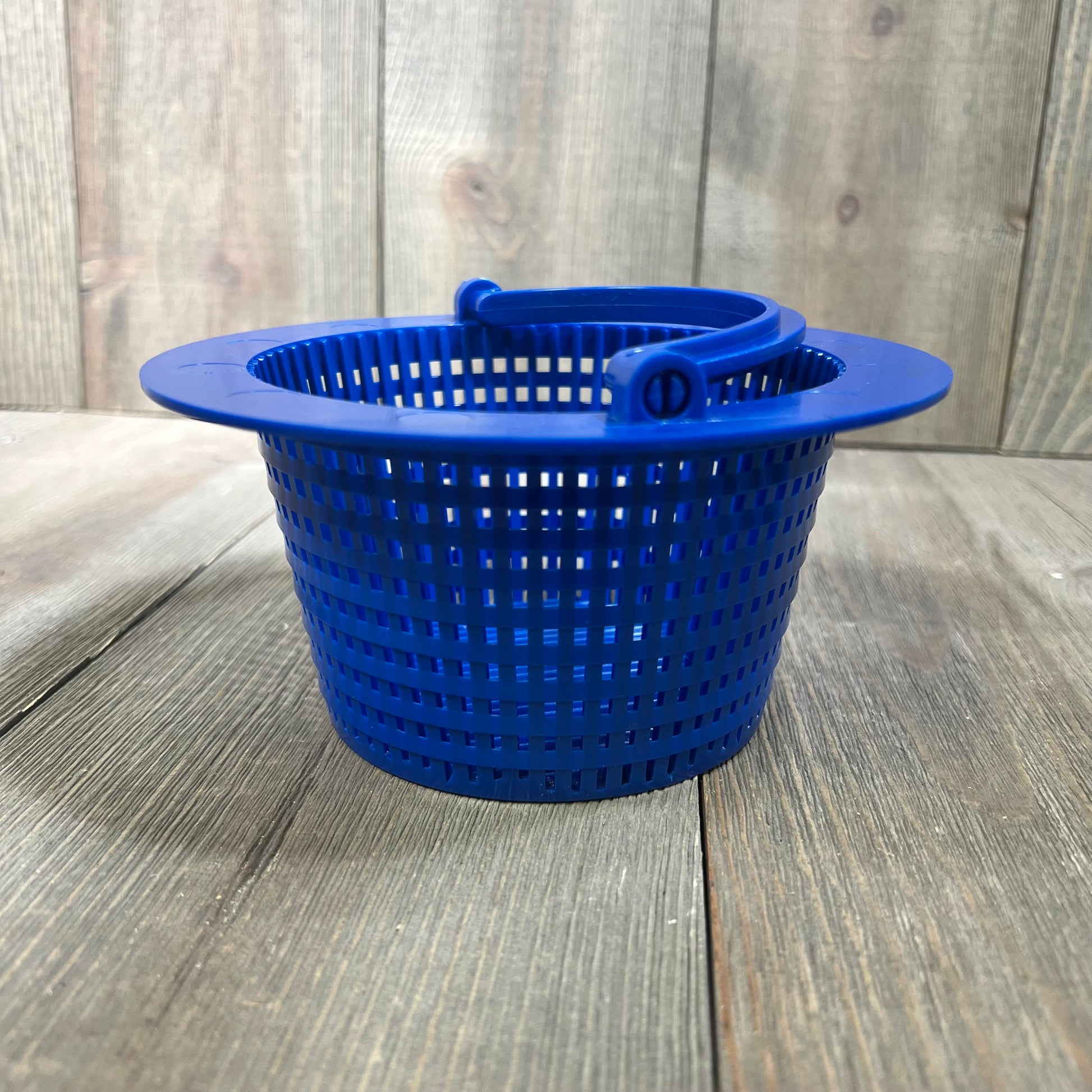 Blue pool skimmer basket with handle for removing leaves and debris, placed on a wooden surface.