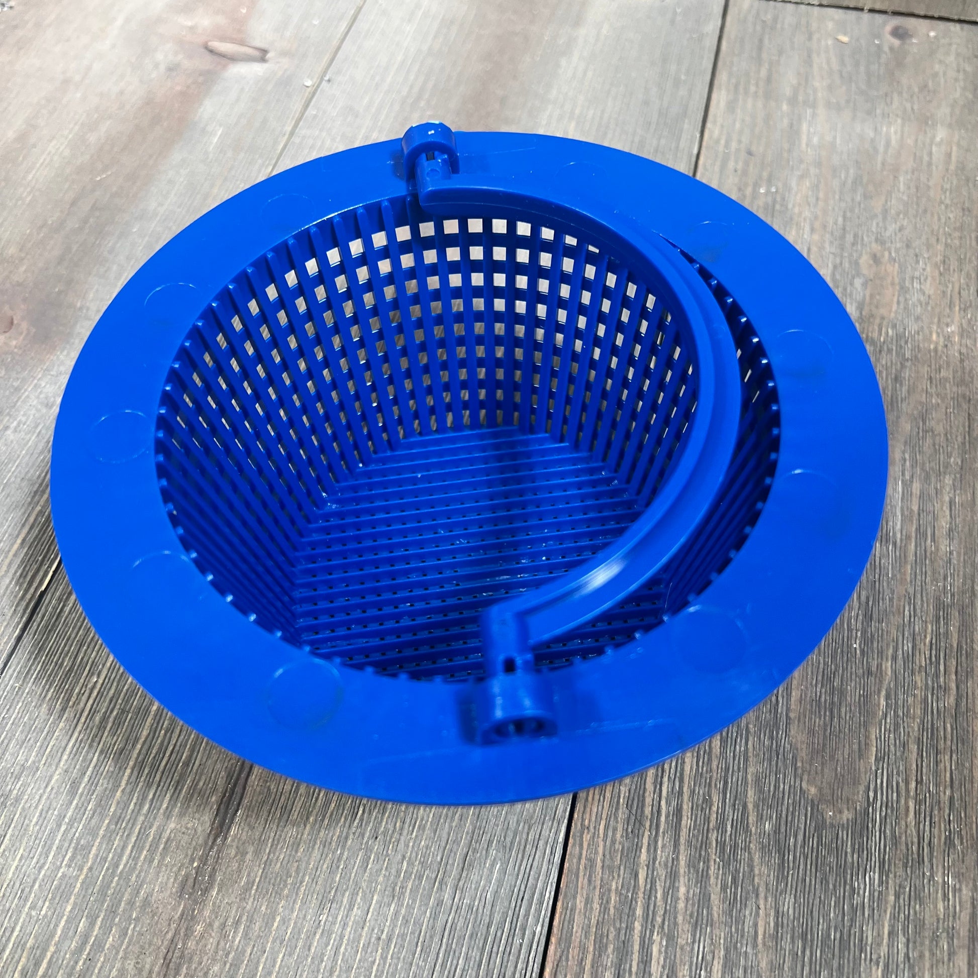 Blue pool skimmer basket with handle on wooden surface.