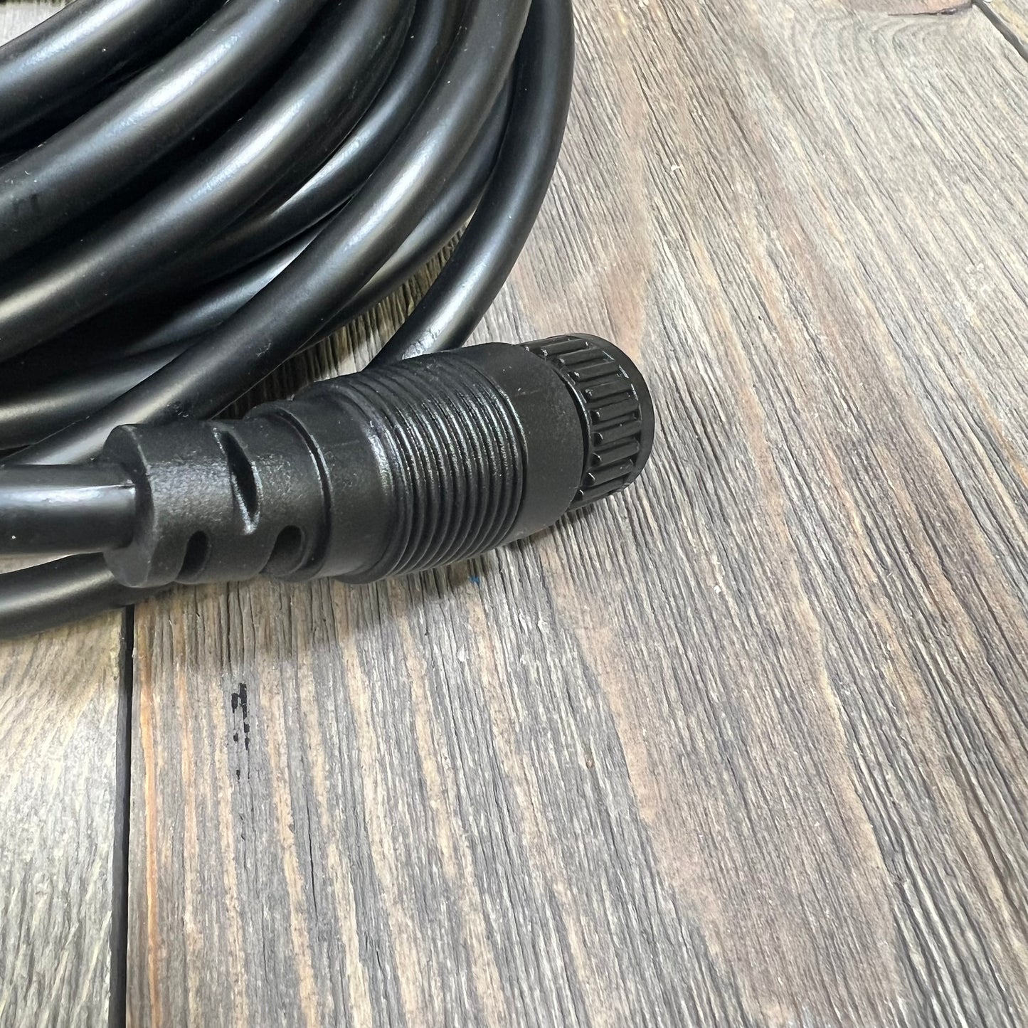 Alt text: Black replacement cable with connector for pool pumps on a wooden surface.
