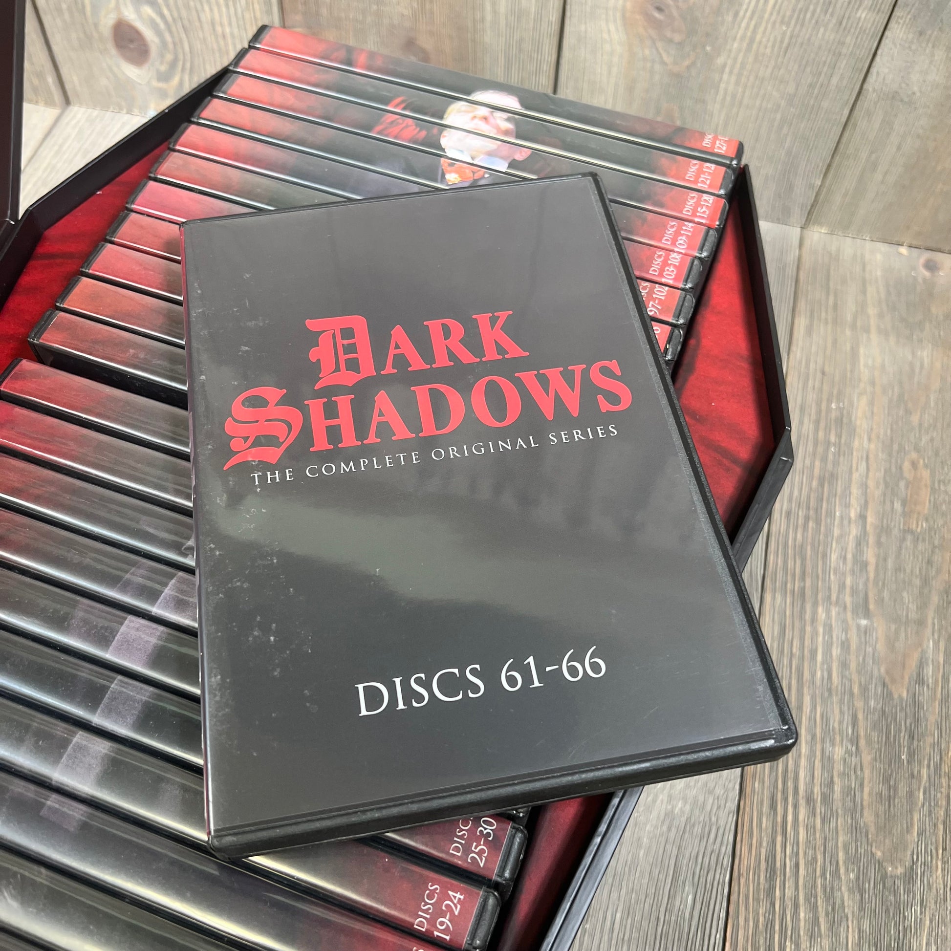 Alt text: Deluxe DVD set of "Dark Shadows: The Complete Original Series" with multiple discs displayed on a wooden surface.