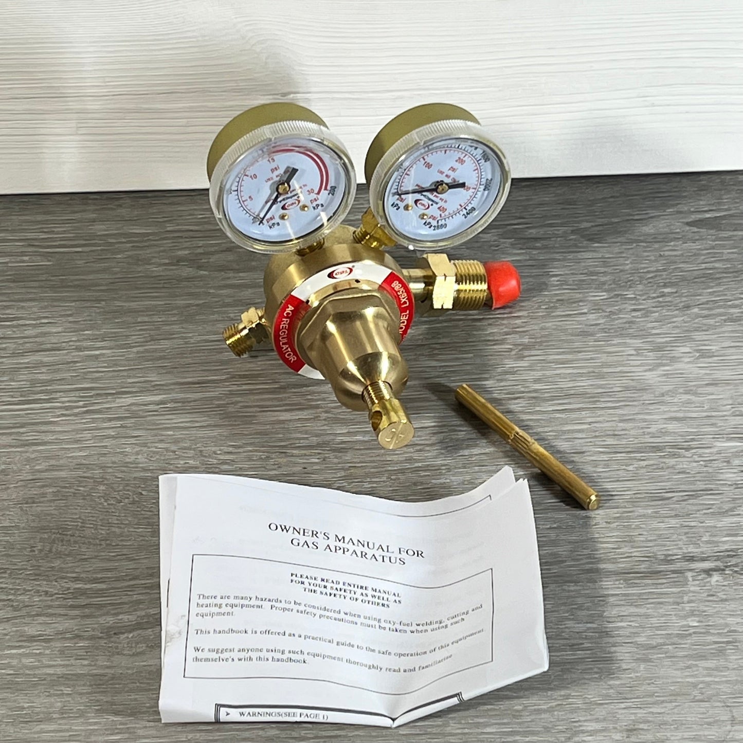 LX65/88 acetylene regulator with dual gauges and CGA510 connection on a gray surface, includes instruction manual.