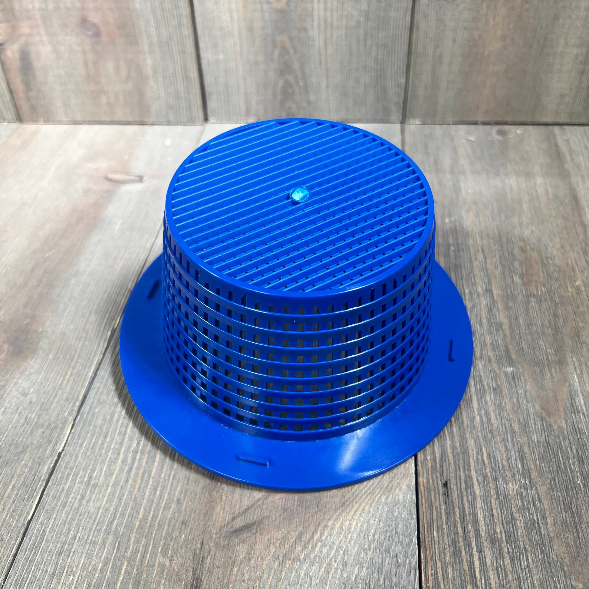 Alt text: Blue pool skimmer basket with handle for leaf and debris removal, placed on a wooden surface.
