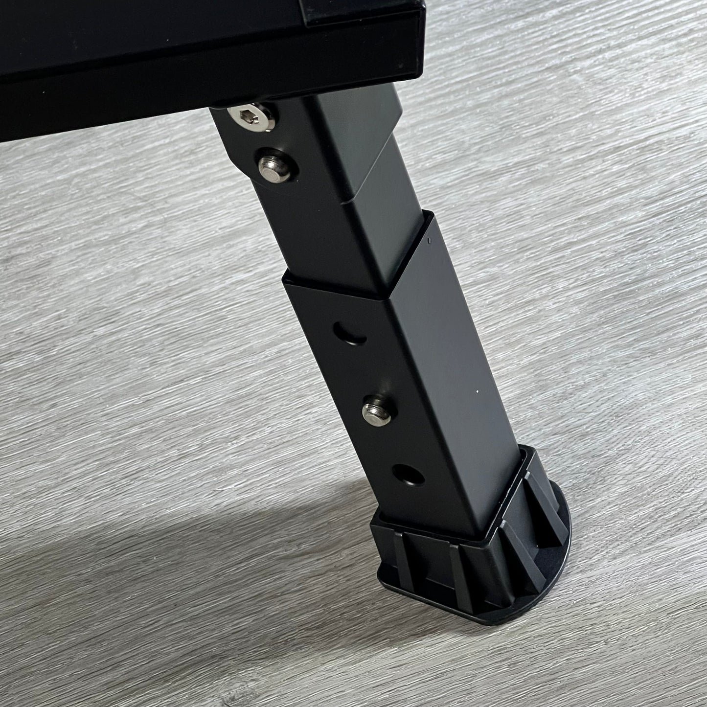 Adjustable black aluminum leg of DEPSUNNY RV step with non-slip rubber foot on wooden floor.