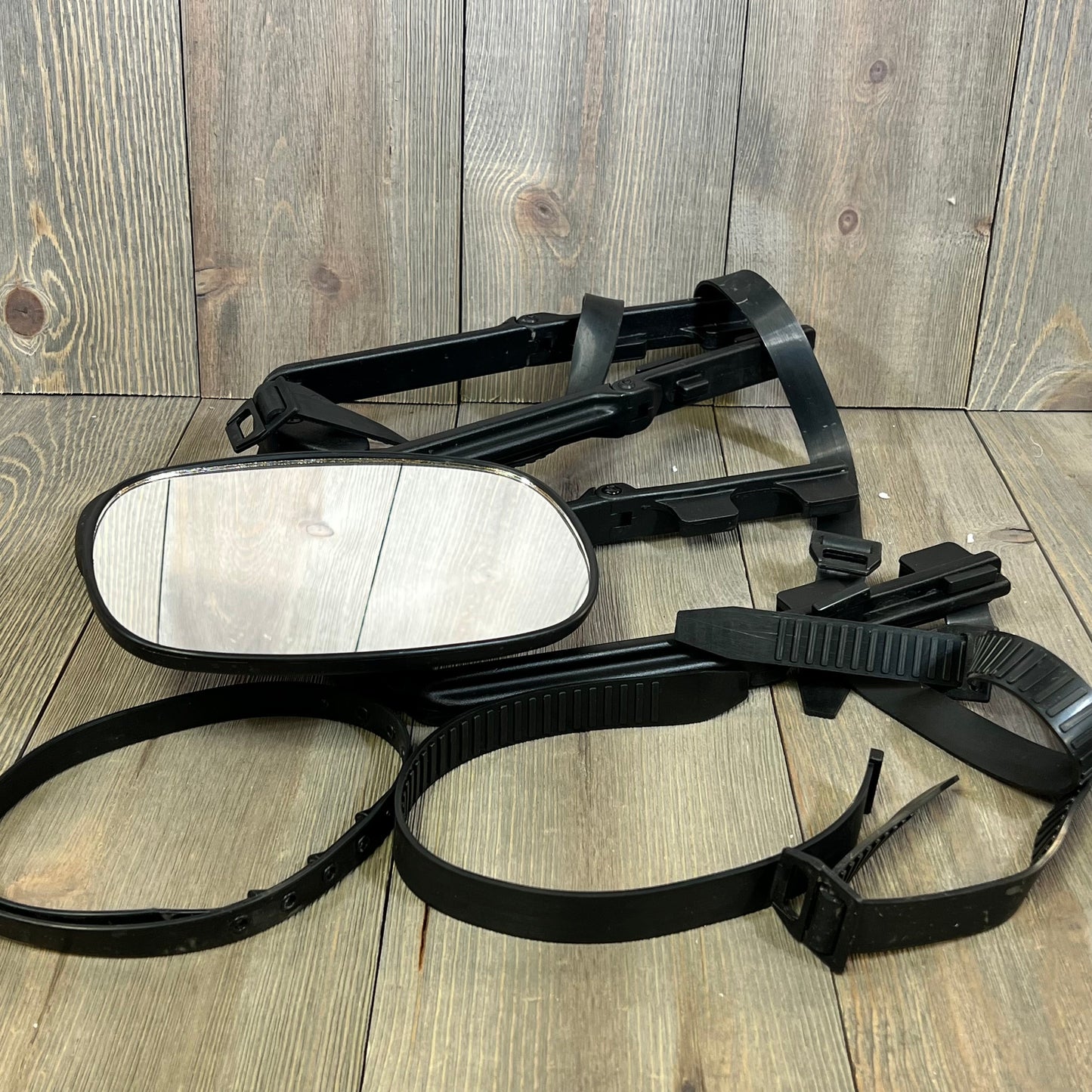 Universal clip-on towing mirror with extenders for pickups and RVs, laid on wooden surface, showcasing adjustable straps.
