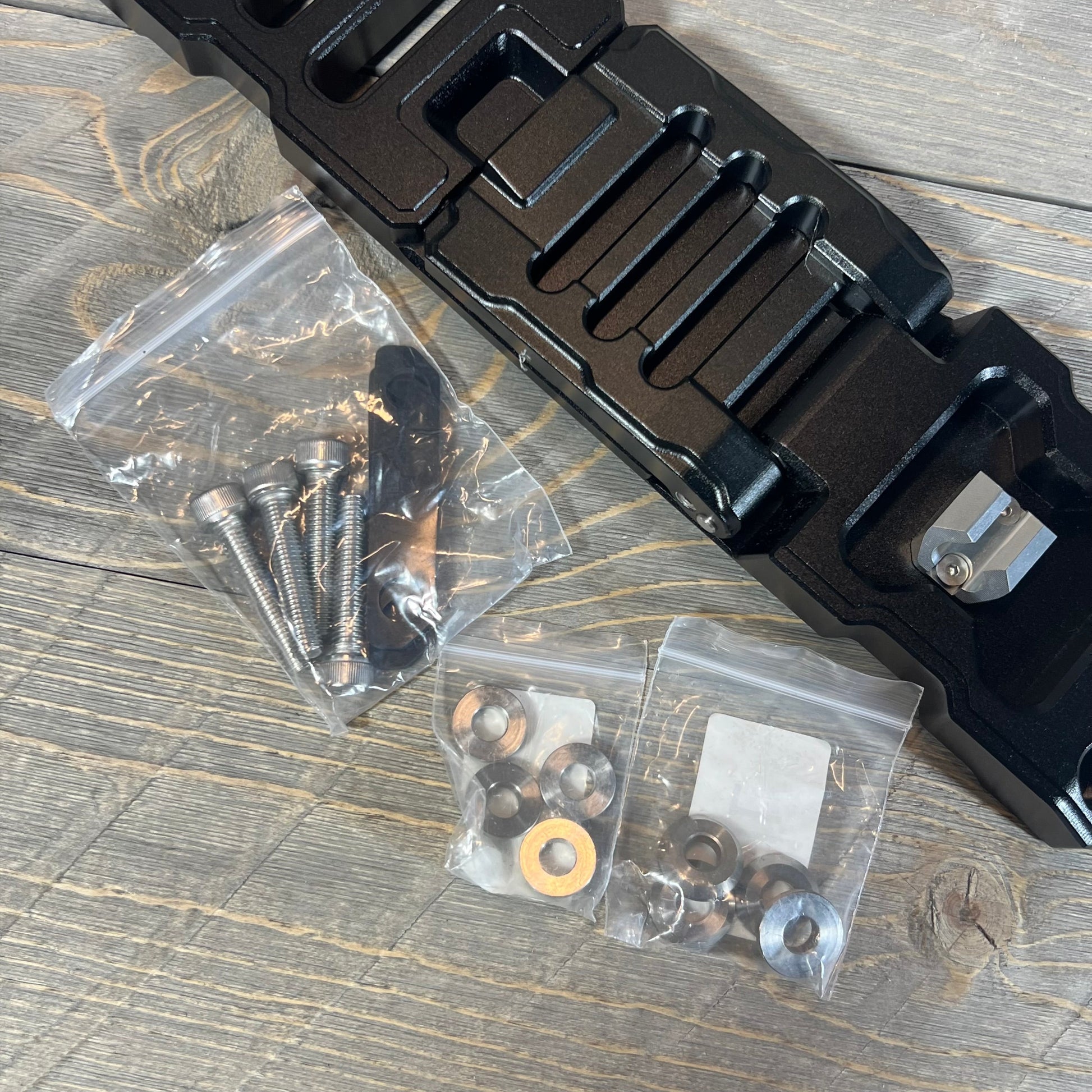 Aluminum alloy door hinge step with installation hardware for Jeep Wrangler & Gladiator 2007-2023 on wood surface.