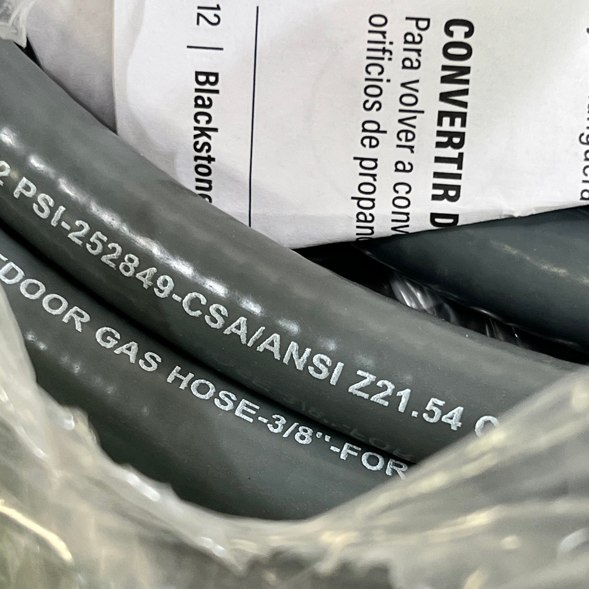 Close-up of Blackstone 5249 Conversion Kit gray gas hose with CSA/ANSI markings for propane to natural gas conversion.