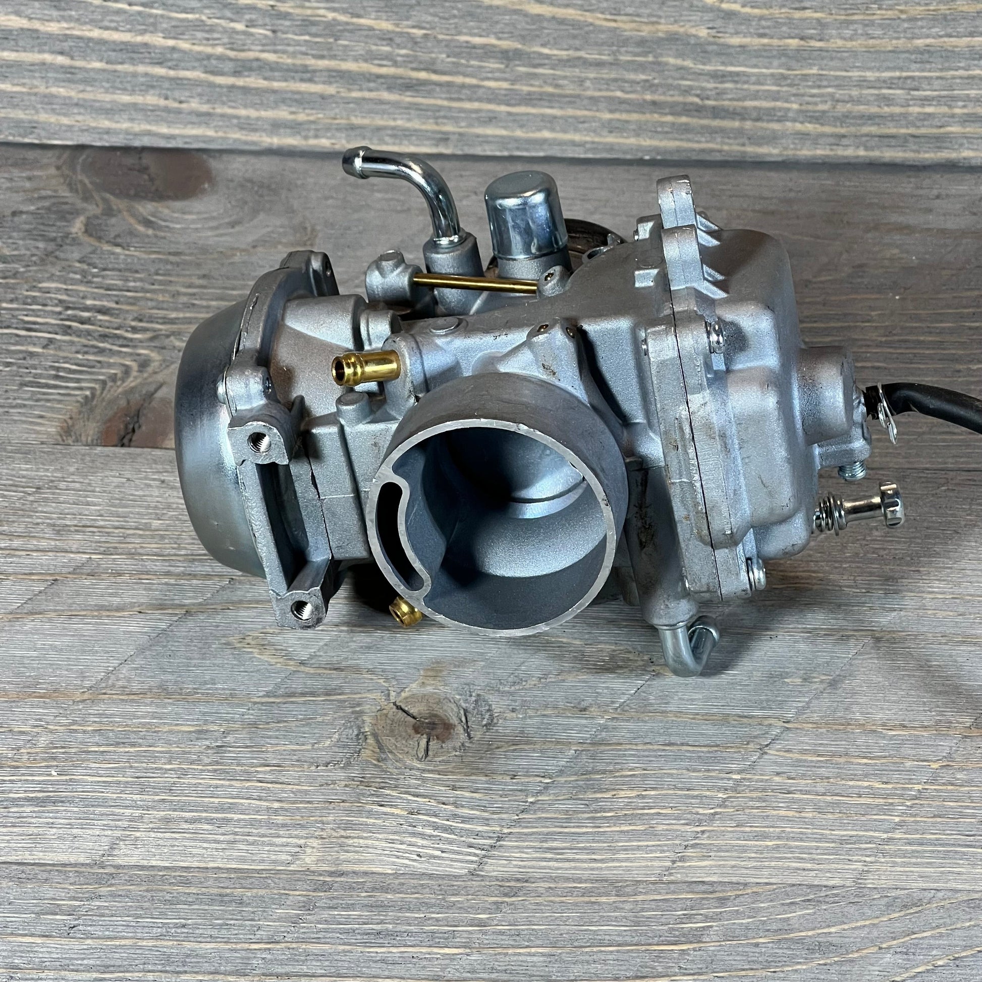 ATV carburetor replacement for Polaris Sportsman 500, 1996-1998, showcasing intricate metal design on wood surface.