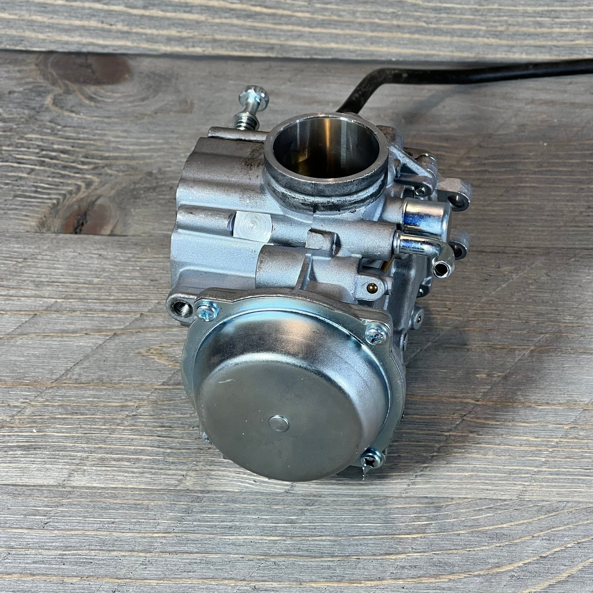 ATV carburetor replacement for Polaris Sportsman 500, detailed view on wooden surface.