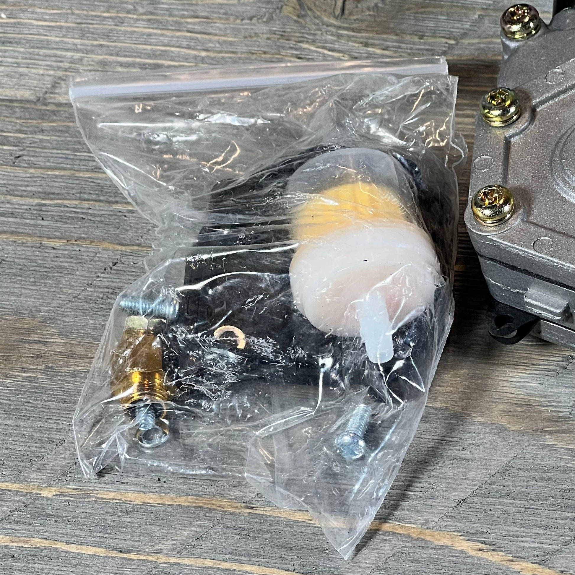 ATV carburetor replacement kit for Polaris Sportsman 500, featuring parts in a clear plastic bag on a wooden surface.