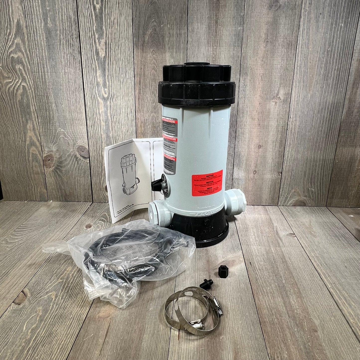 Automatic chlorinator feeder with accessories on wooden background, ideal for pool and garden maintenance.