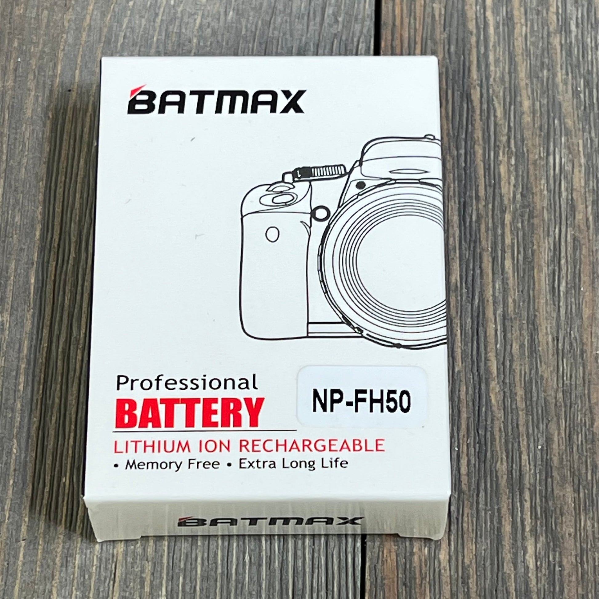 Batmax NP-FH50 battery packaging on wooden surface, showcasing compatibility with Sony Alpha DSLR and Cyber-Shot cameras.