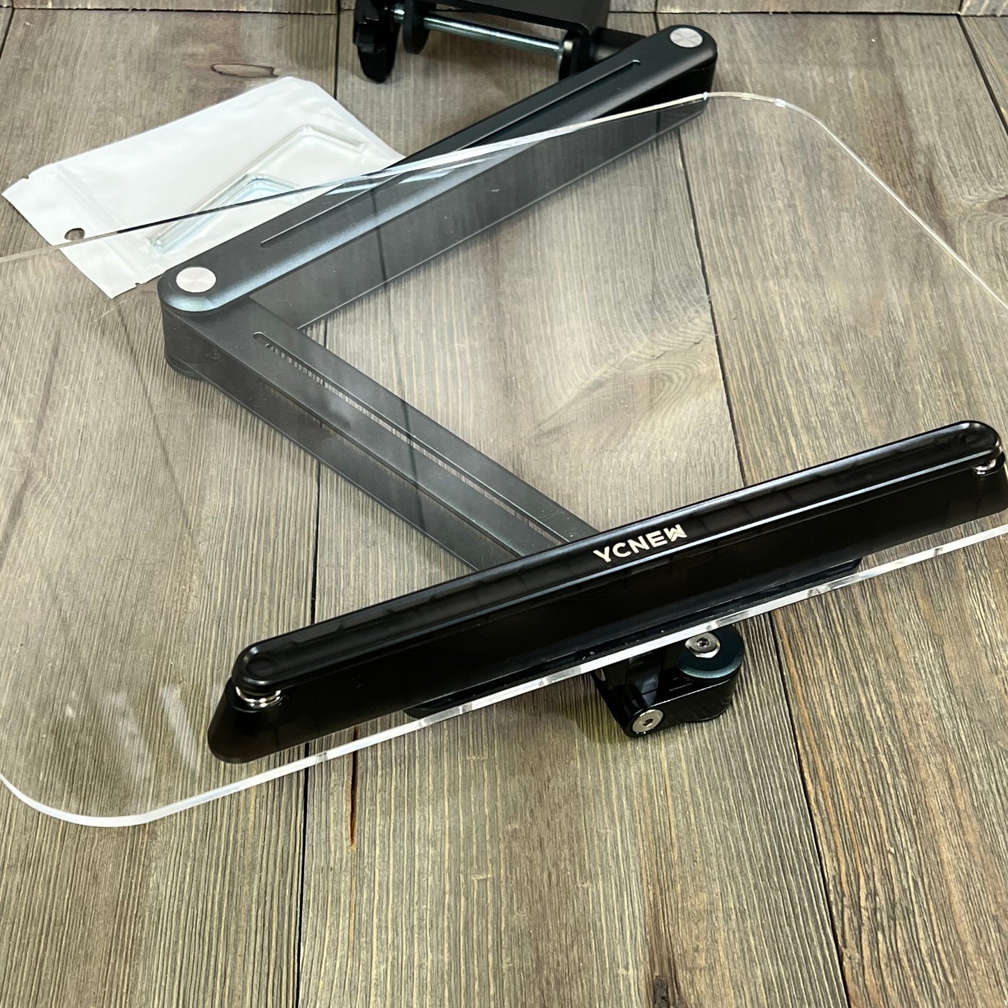 Ergonomic gray desk clamp acrylic book stand with adjustable height and rotating base for reading recipes and sheet music.