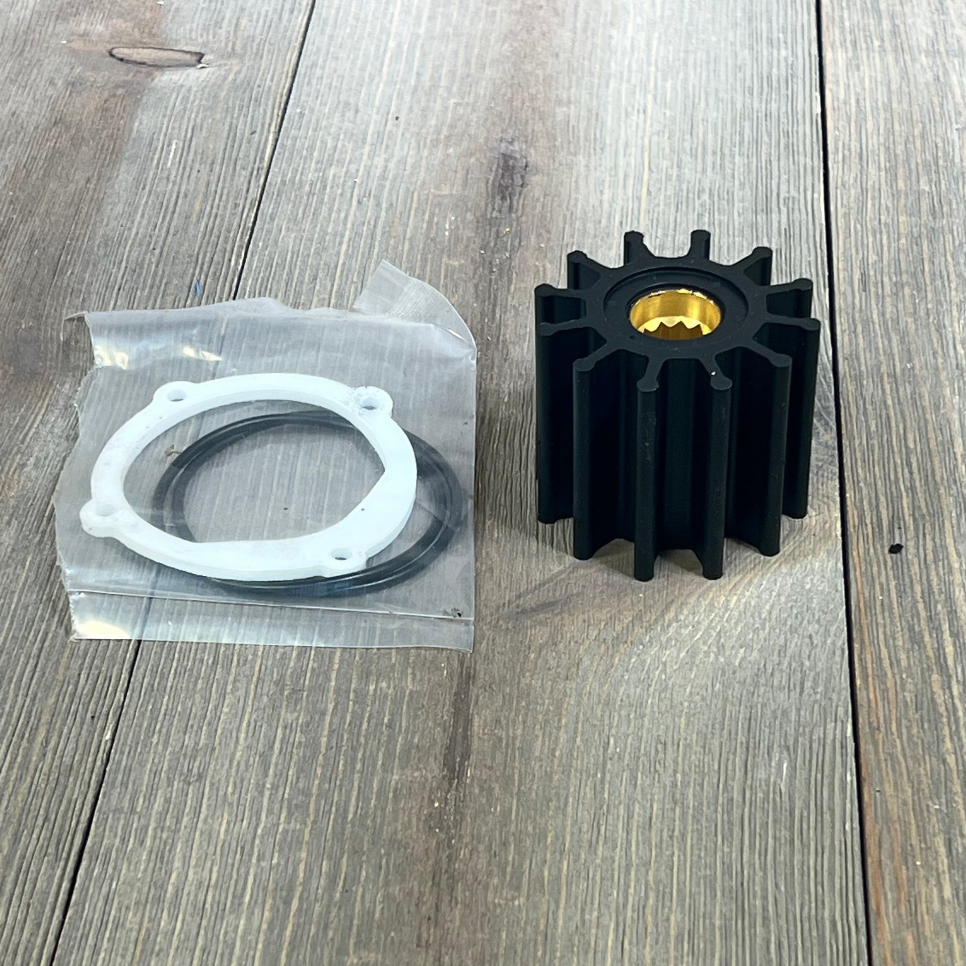 Water pump impeller repair kit for Johnson and Yanmar, featuring black impeller and gasket on wooden surface.
