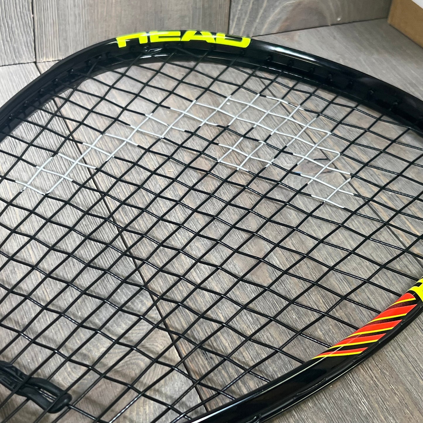 Close-up of the HEAD CPS Heat Racquetball Racquet strings and frame, showcasing its durable design and vibrant colors.