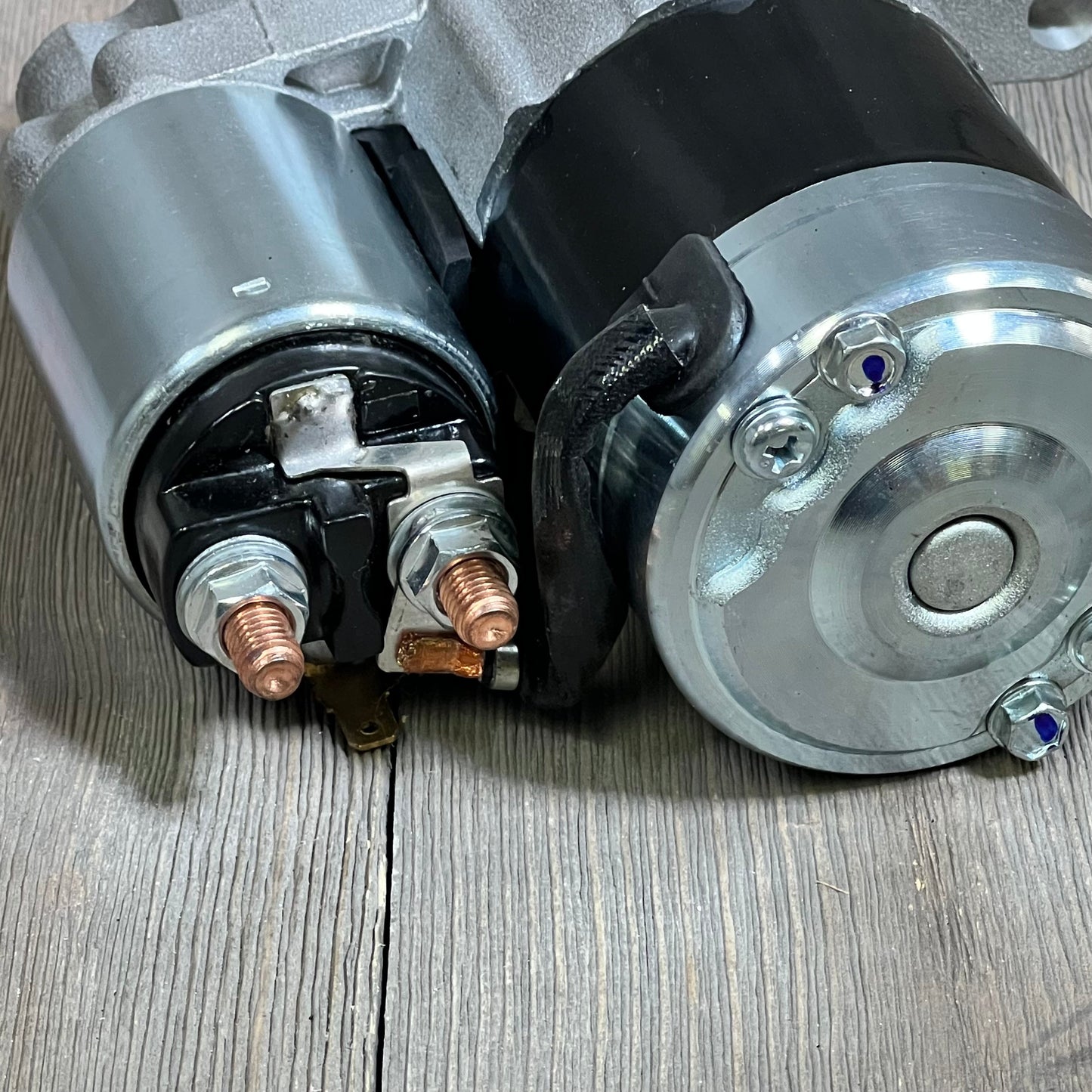 Starter motor for Grand Cherokee 4.0L L6 2003-2004, close-up view of terminals and housing on textured surface.