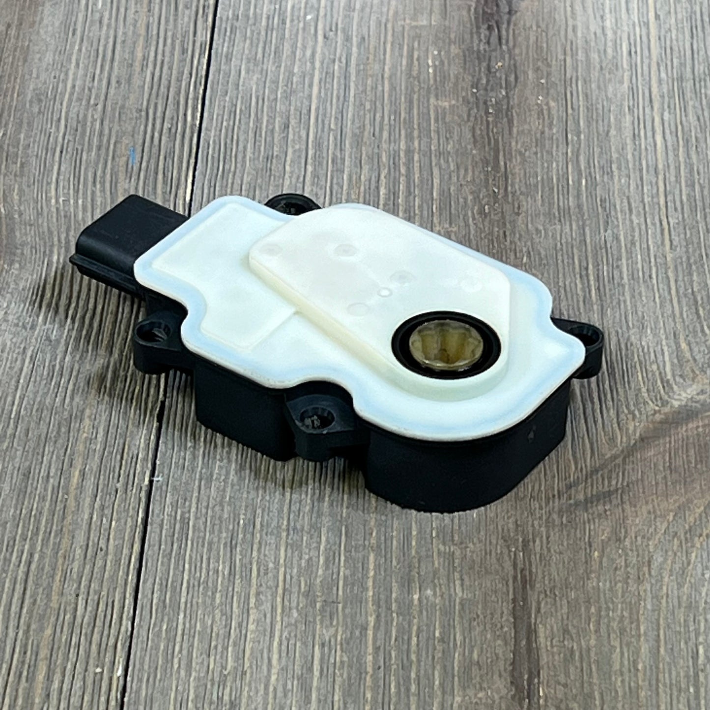 Air actuator motor for Nissan Rogue 2017-2020, featuring a robust black and white design on a wooden surface.