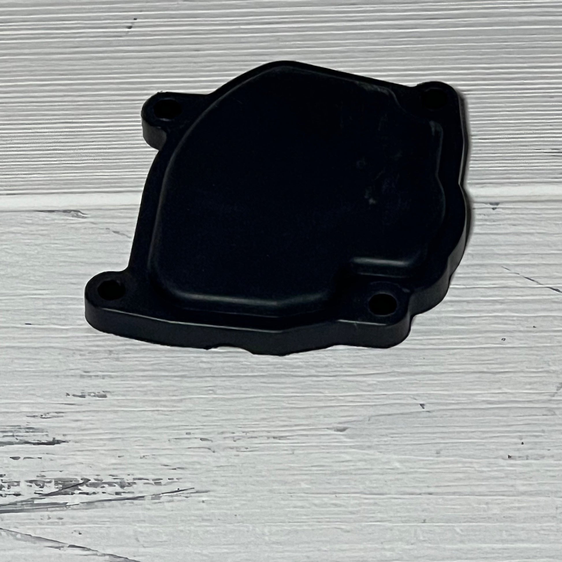 Black Caltric carburetor cover for Suzuki LT-F250 Quadrunner 250 2X4, ideal for 1990-1993 models, on wooden surface.