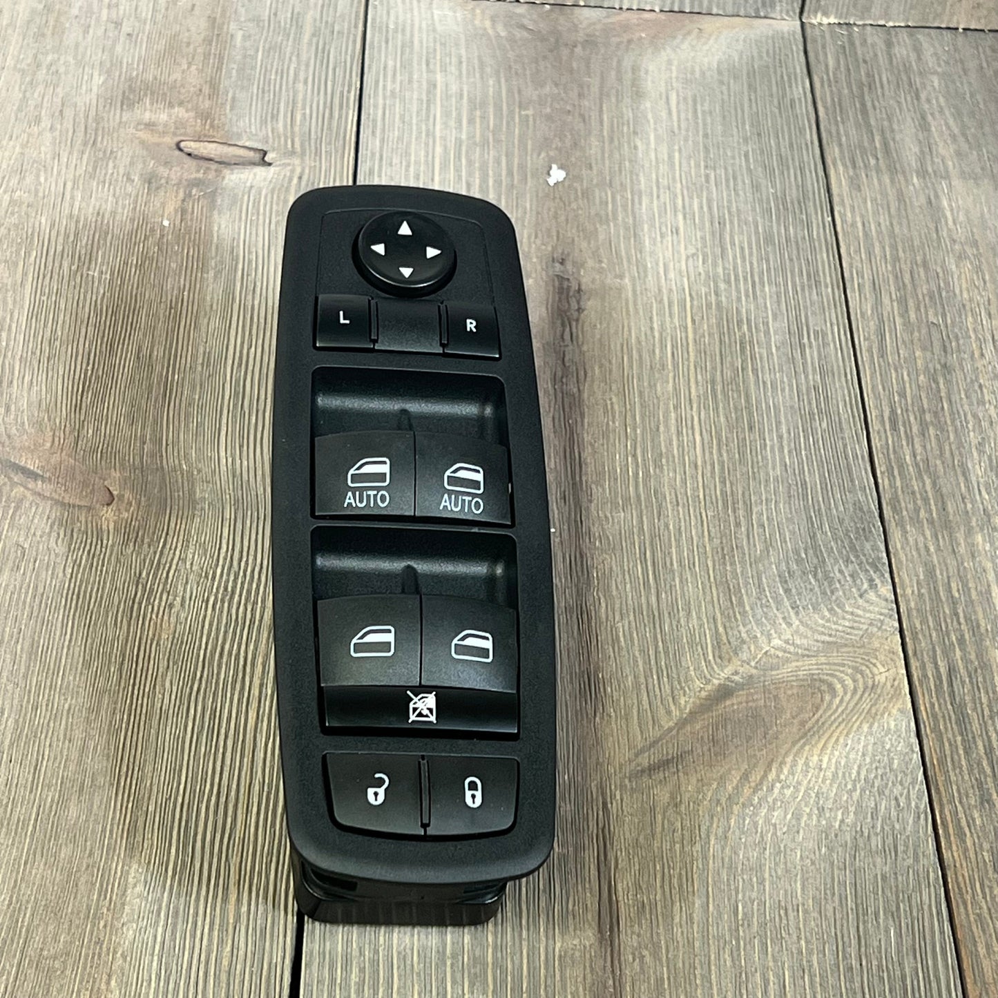 Master Power Window Switch for Chrysler 300, 200, Dodge Charger, Ram 1500-3500, top view on wood background.