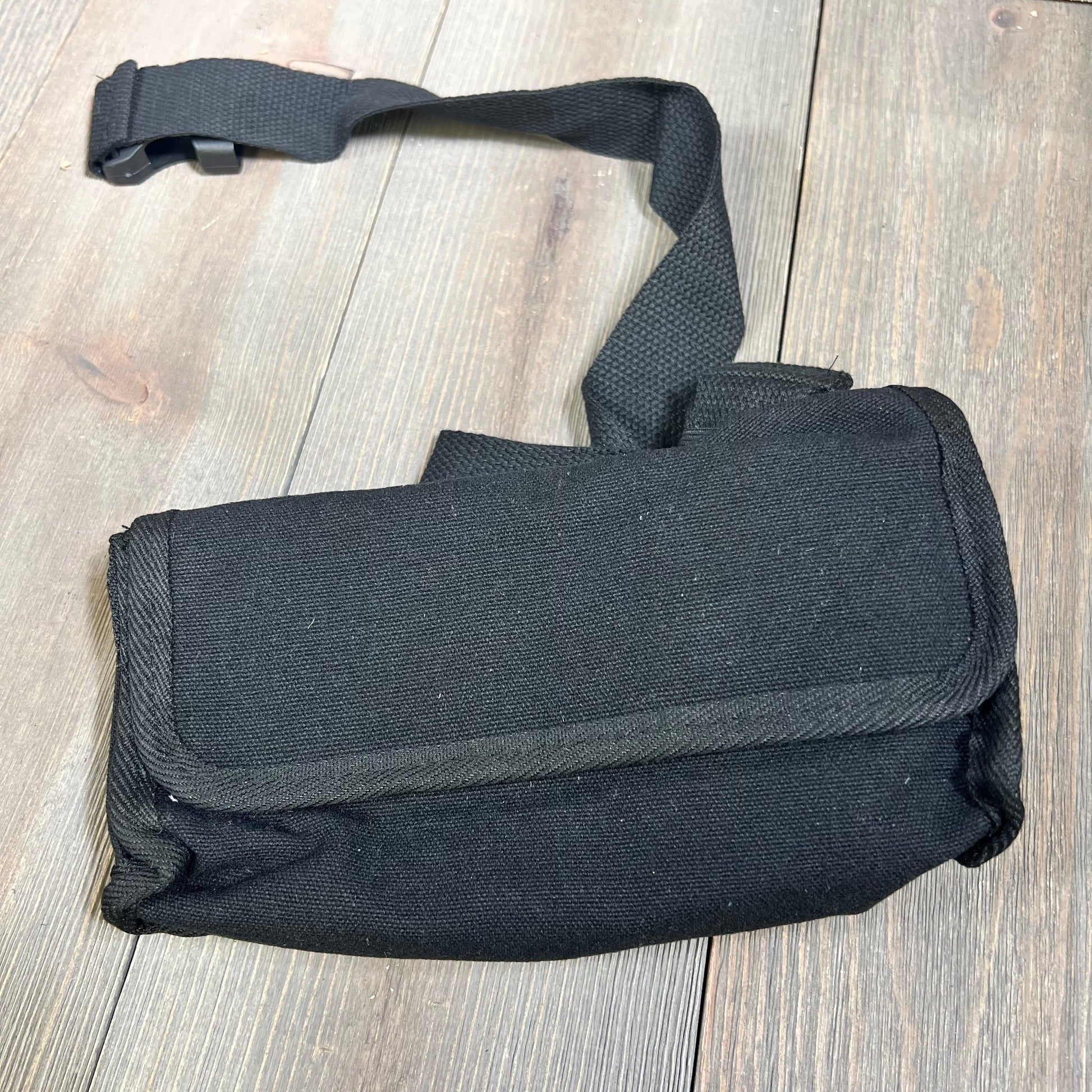 Black Cunno fanny pack with belt, ideal for waiters and cashiers, on a wooden surface.