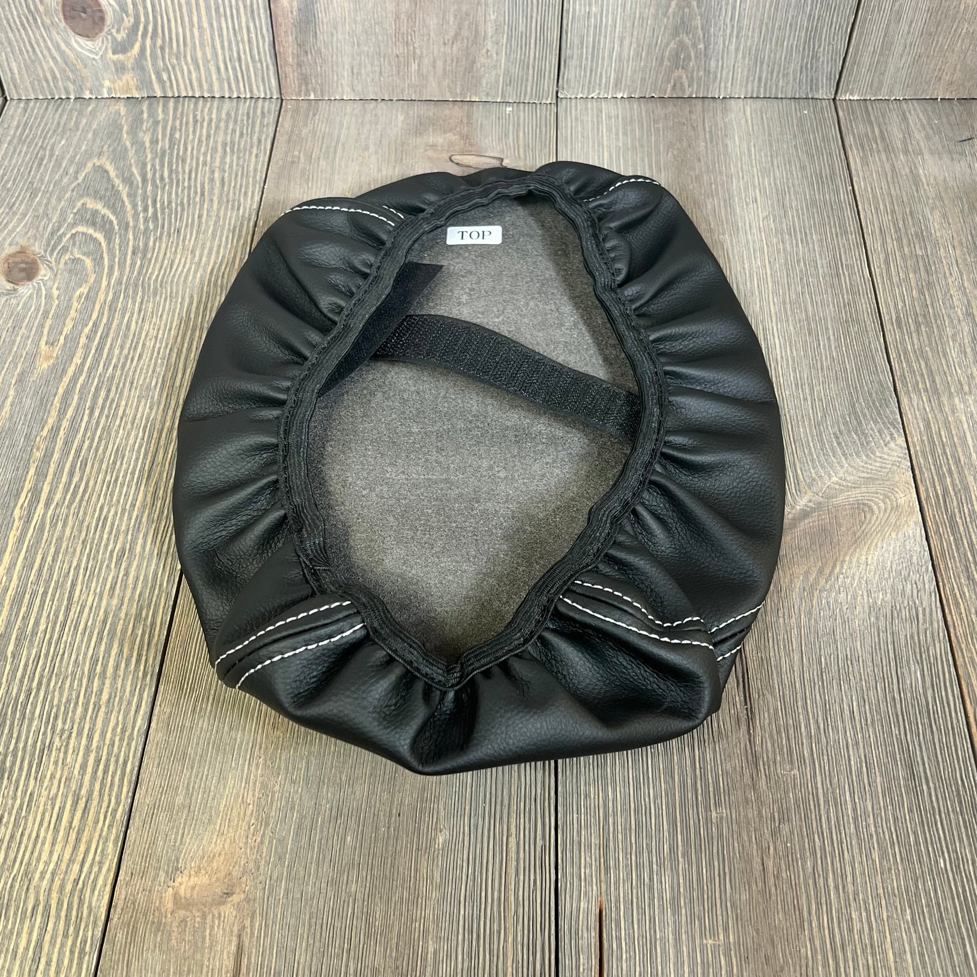 Black leather armrest cover with white stitching for 2024-2025 Ford Explorer, showing elastic band and interior lining.