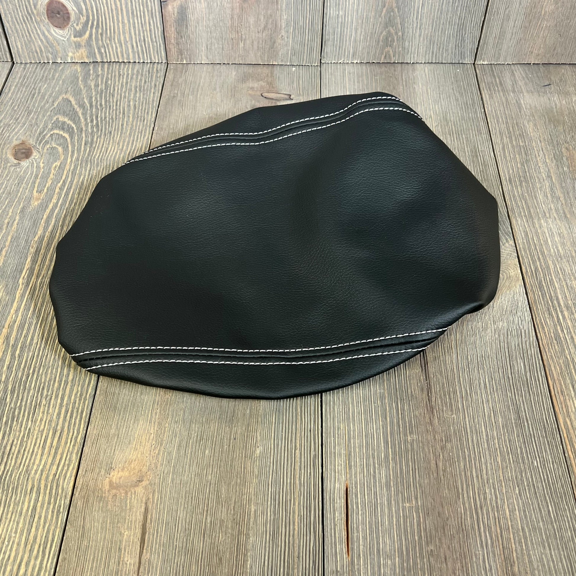 Black leather armrest cover with white stitching for 2024-2025 Ford Explorer, enhancing interior and protecting console.