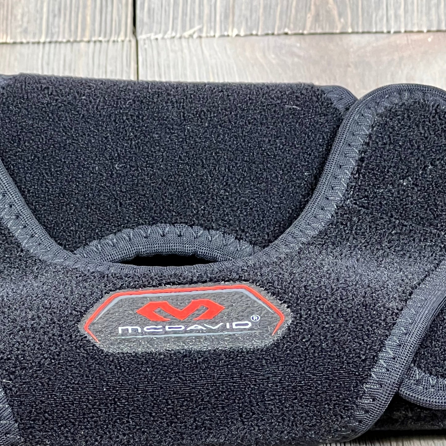 Black McDavid MD4201 Knee Wrap with reinforced stays, size small, offering versatile knee support and comfort.