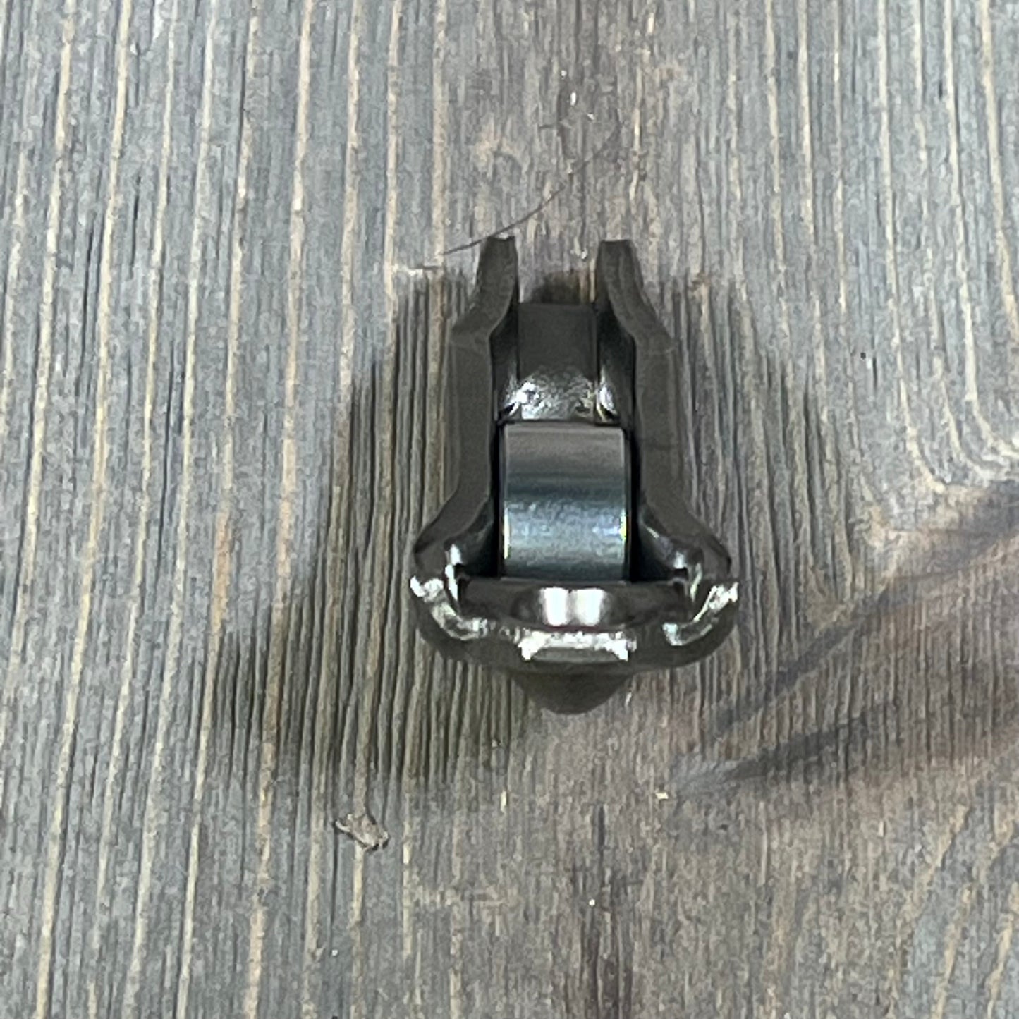 Ford 3L3Z-6564-BA Rocker Arm Valve Assembly on wooden surface, showcasing durable metal construction.