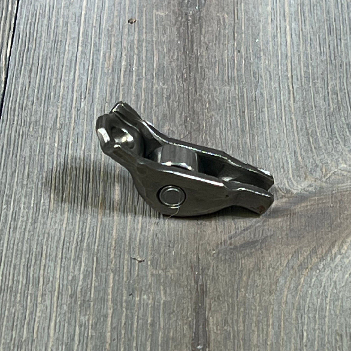 Ford 3L3Z-6564-BA Rocker Arm Valve Assembly on wooden surface, showcasing durable metal construction.