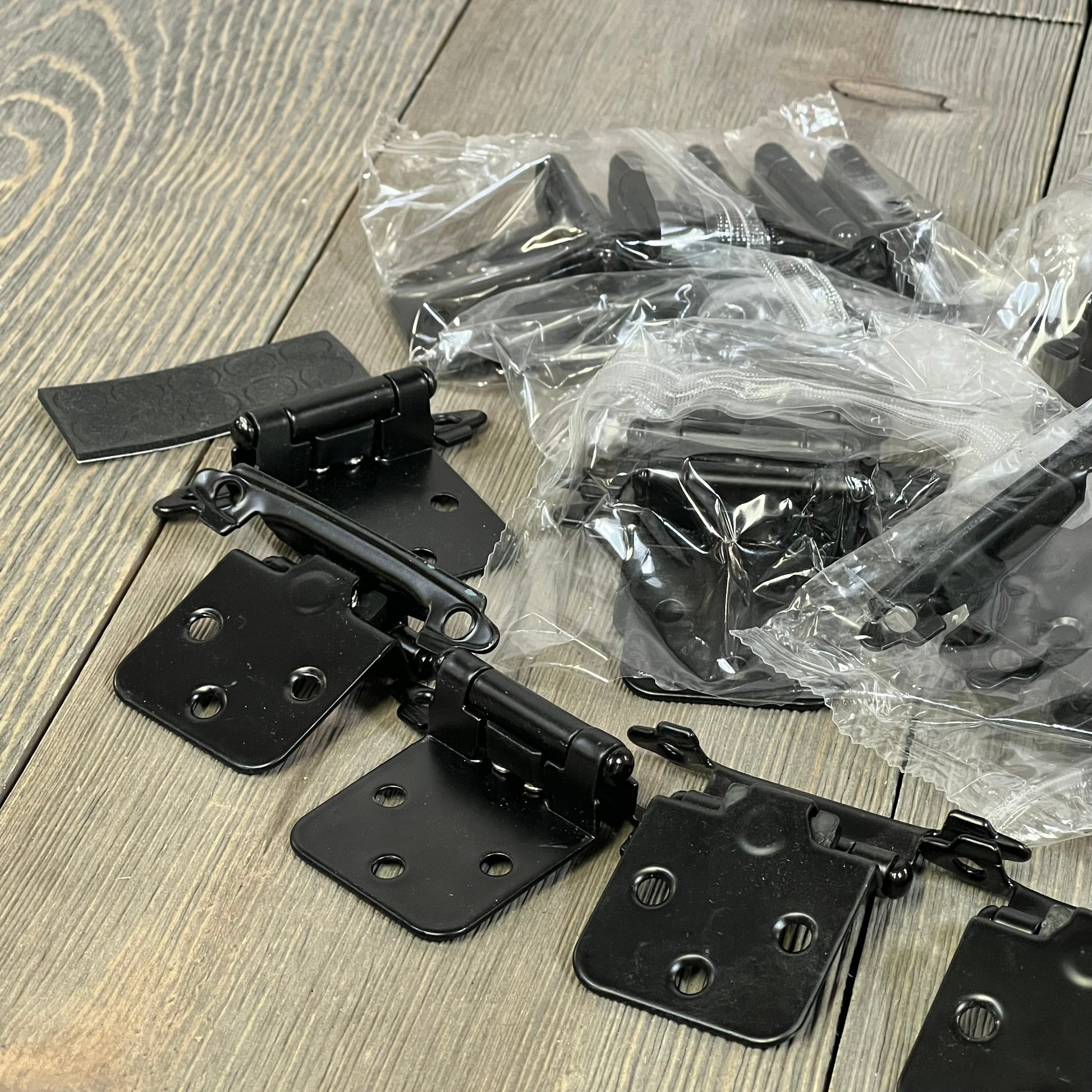 Black 1/2 inch overlay cabinet door hinges, 30 pack, shown on a wooden surface, ideal for kitchen cabinets.