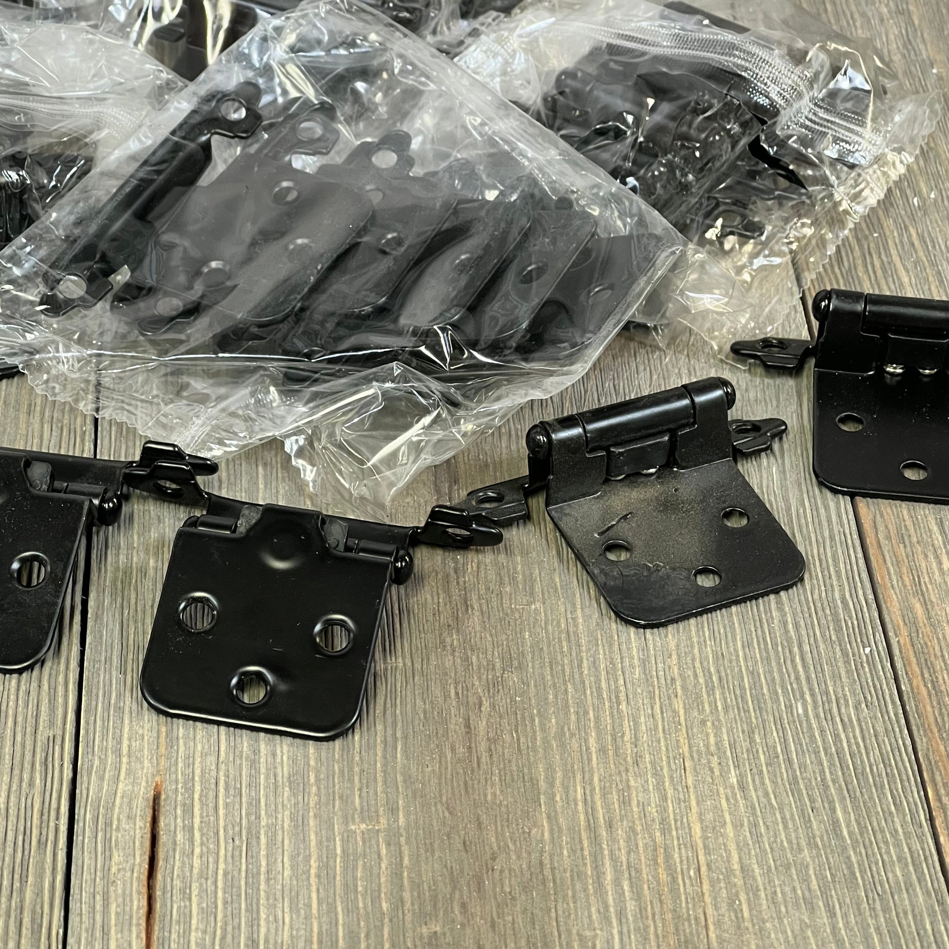 Black 1/2 inch overlay cabinet door hinges, 30 pack shown on wooden surface, ideal for kitchen cupboards.