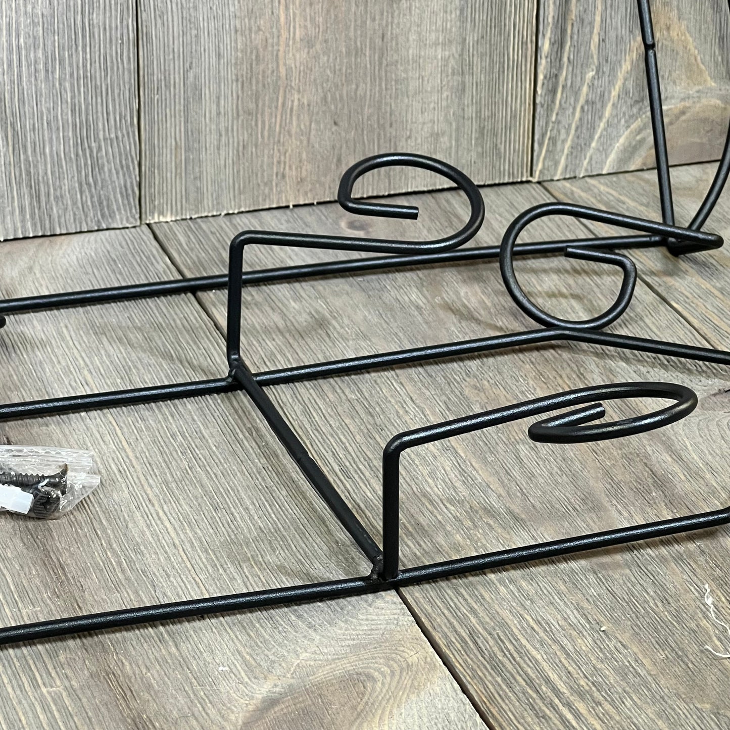 Black metal wall plate holder with three tiers, ideal for displaying dishes or decorative plates. Includes mounting hardware.