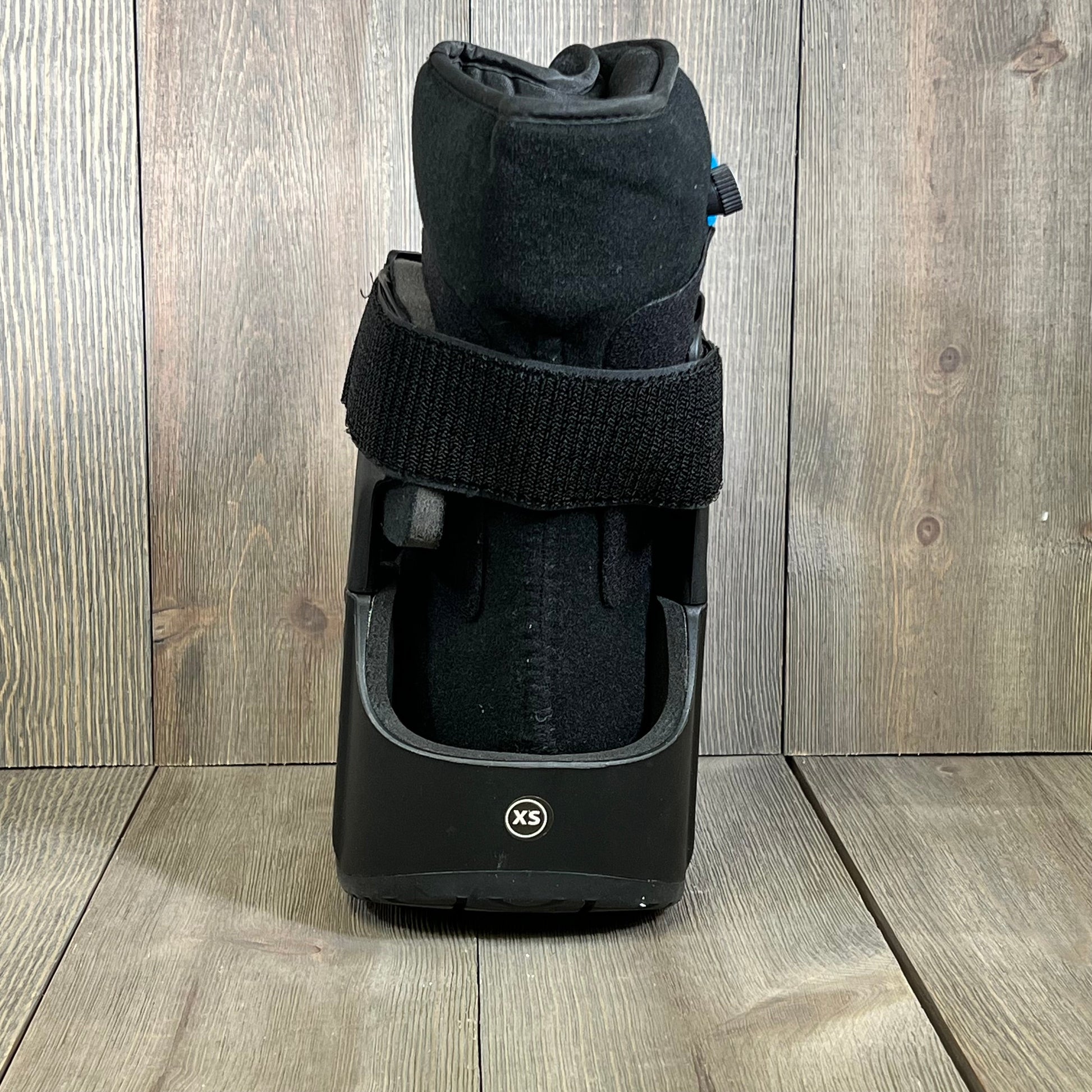 Black short air cam walker fracture boot in extra small, showcasing durable design on wooden floor background.