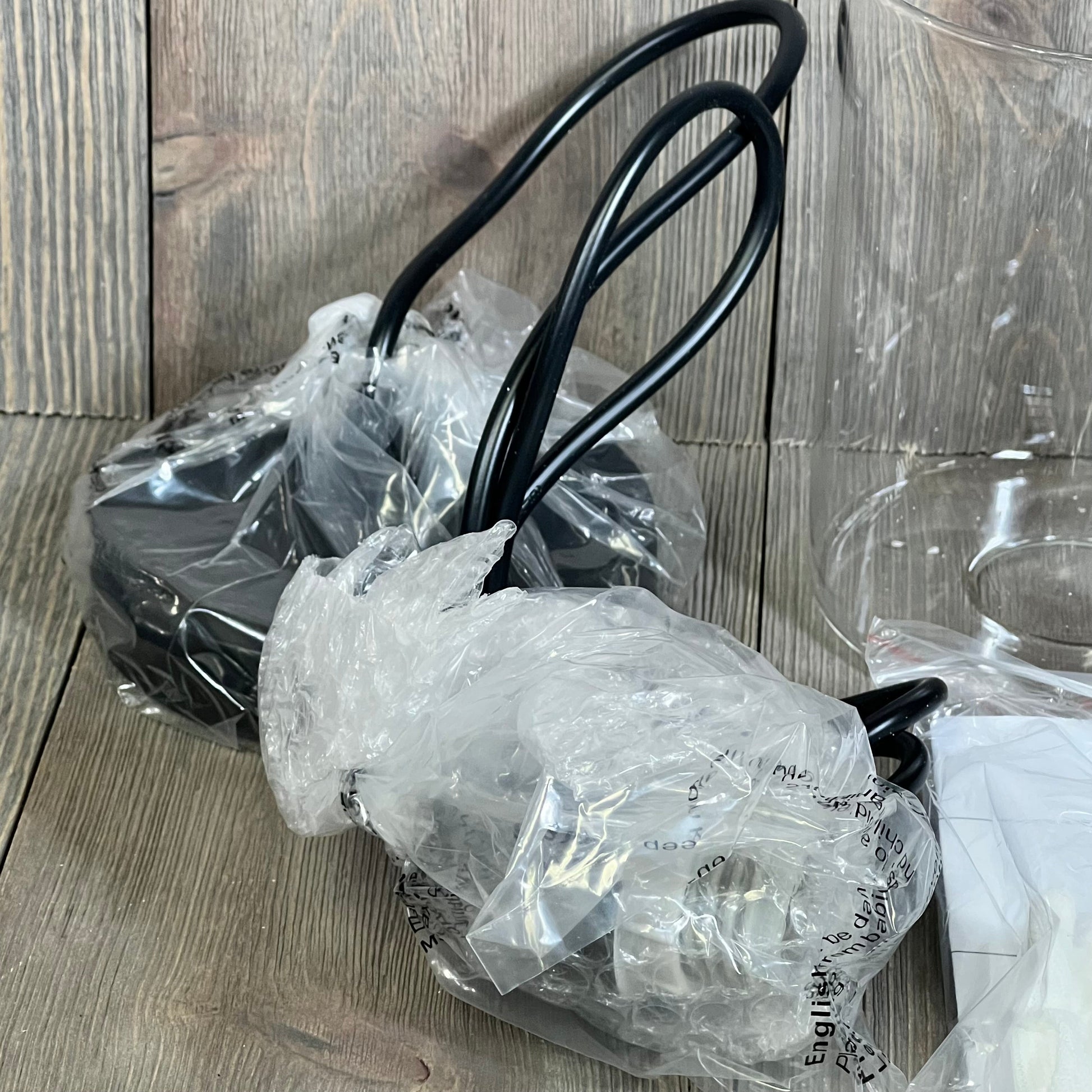 Black farmhouse pendant light with glass shade, featuring adjustable hanging cords, packaged securely for shipping.