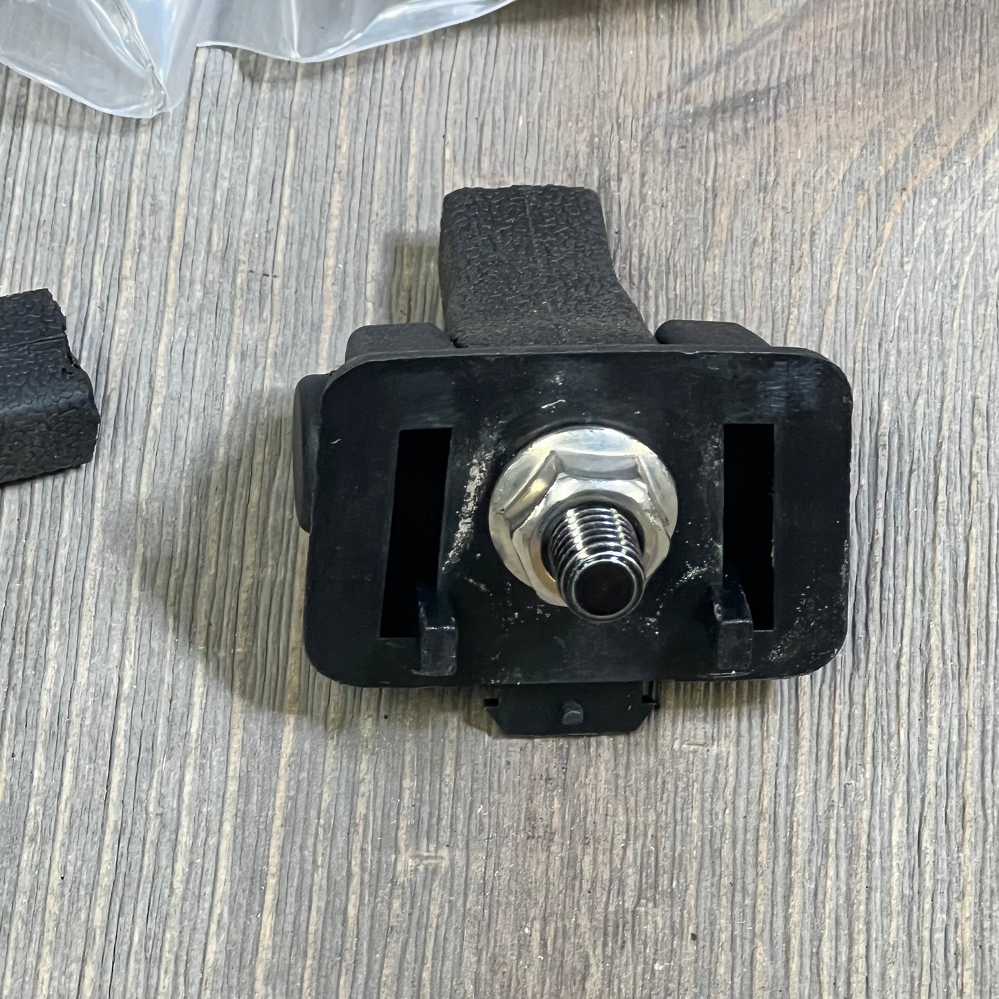 Black Jeep TJ hood latch component on wooden surface, showcasing sturdy design for 1997-2006 Wrangler models.