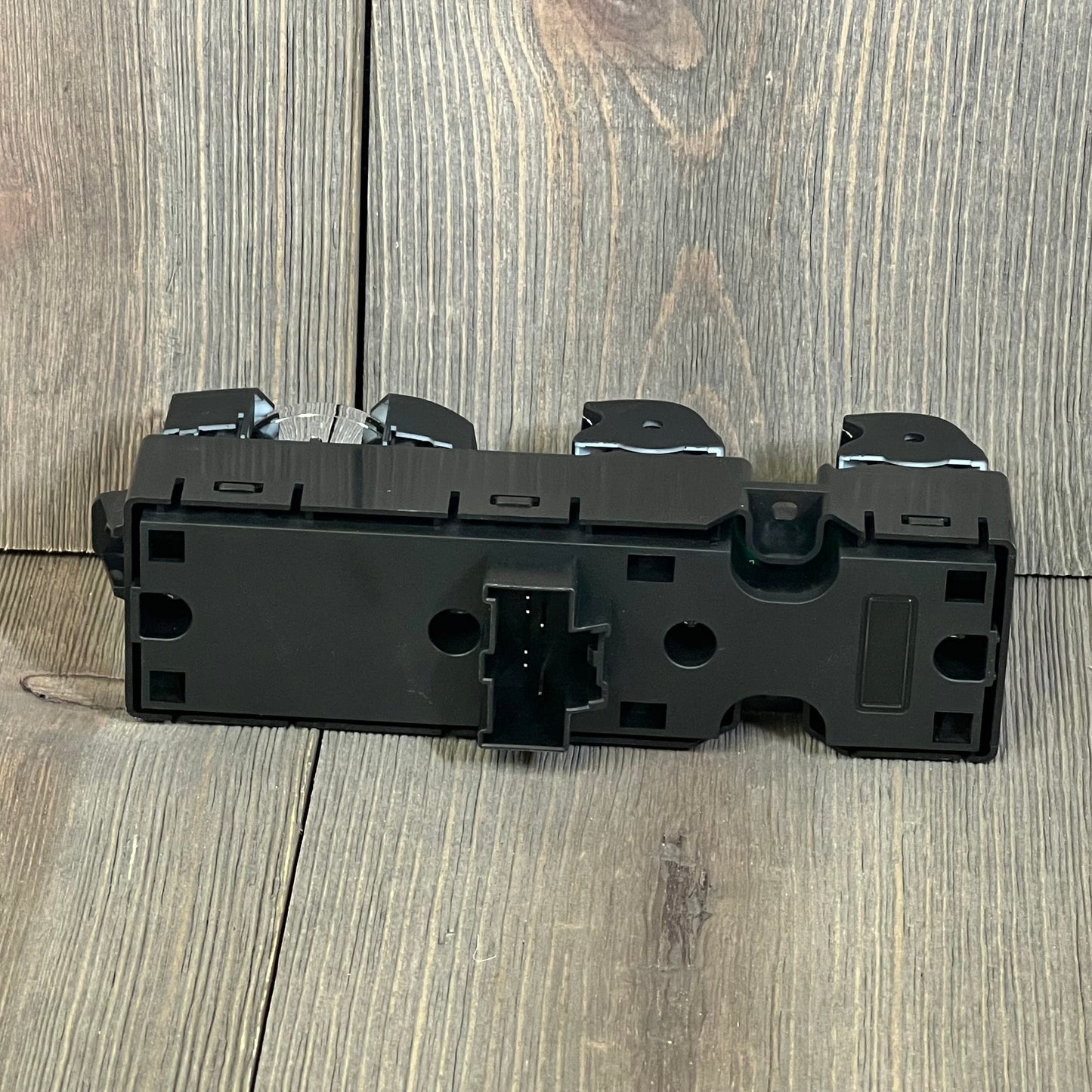 Black Motoforti power window switch for Ford vehicles, showcasing rear view with connector details on a wooden surface.