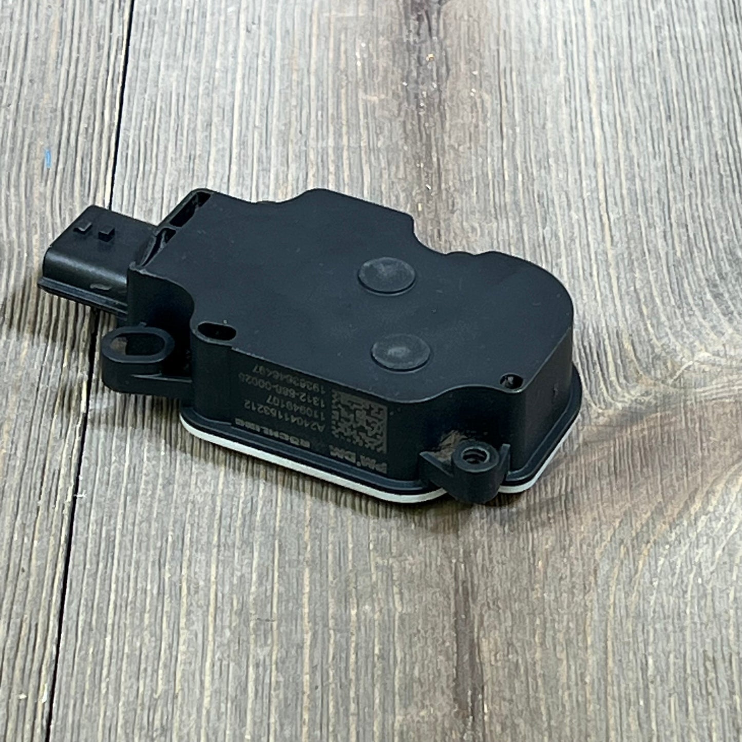 Black LENMISO shutter grille air actuator motor for 2017-2020 Nissan Rogue on wooden surface.
