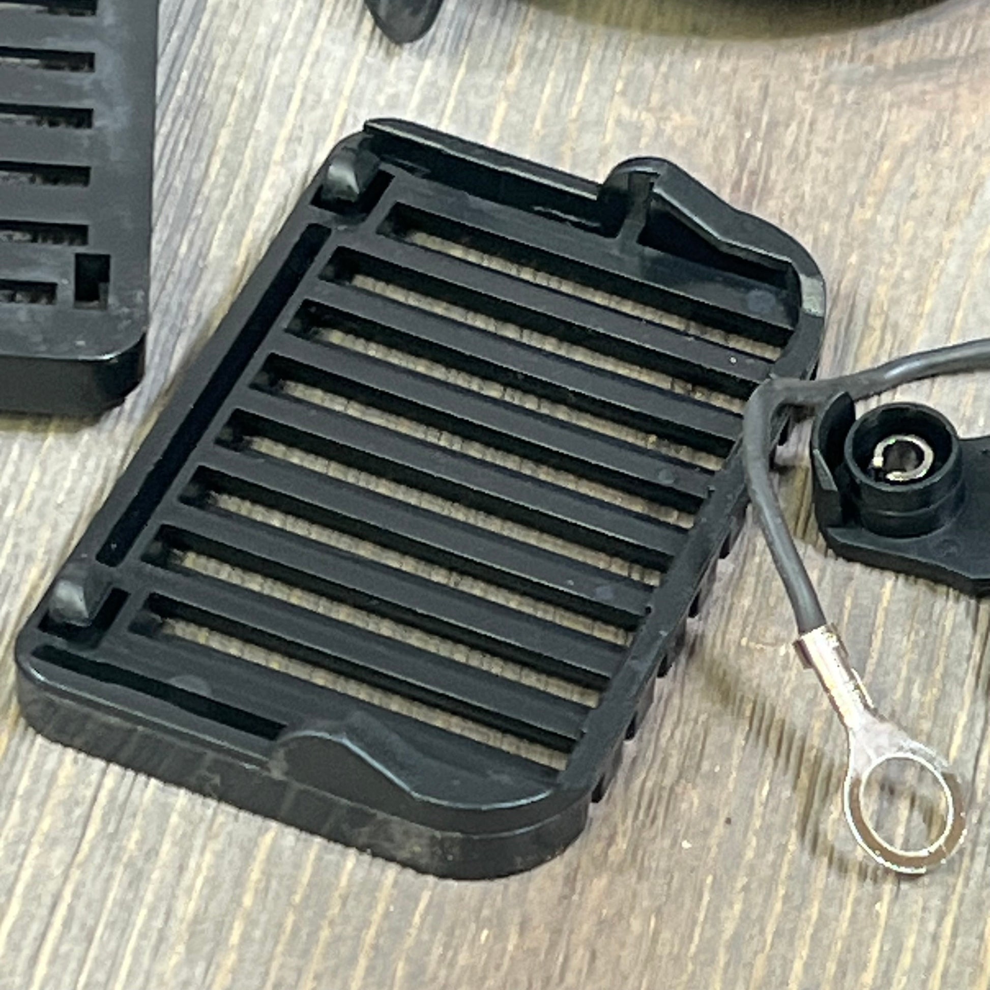 Black car horn grill and wiring for Honda Civic and Acura, featuring durable design and easy installation on wooden surface.