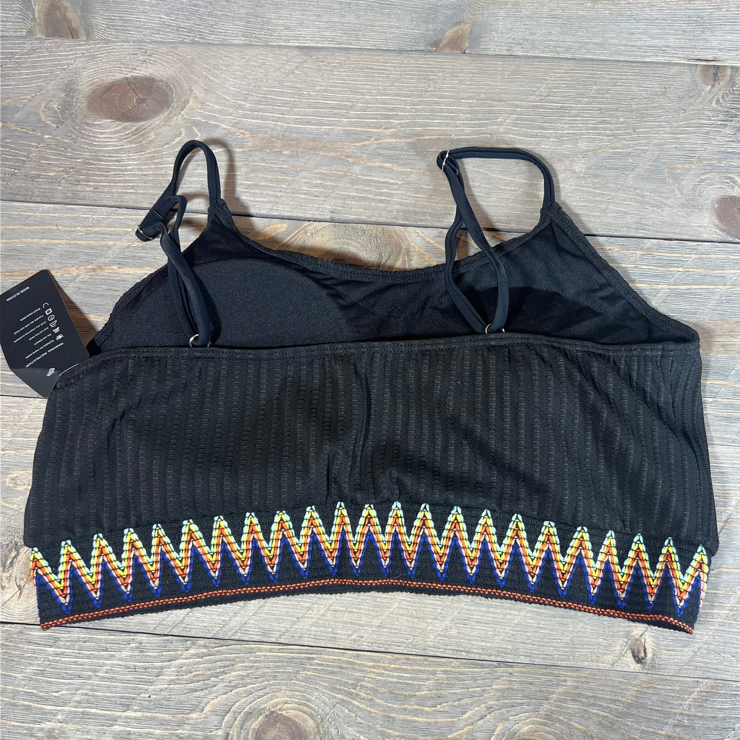 Black ribbed crop top with colorful zigzag trim from Lilosy High Waisted Bikini Set, size XXL, on wooden background.