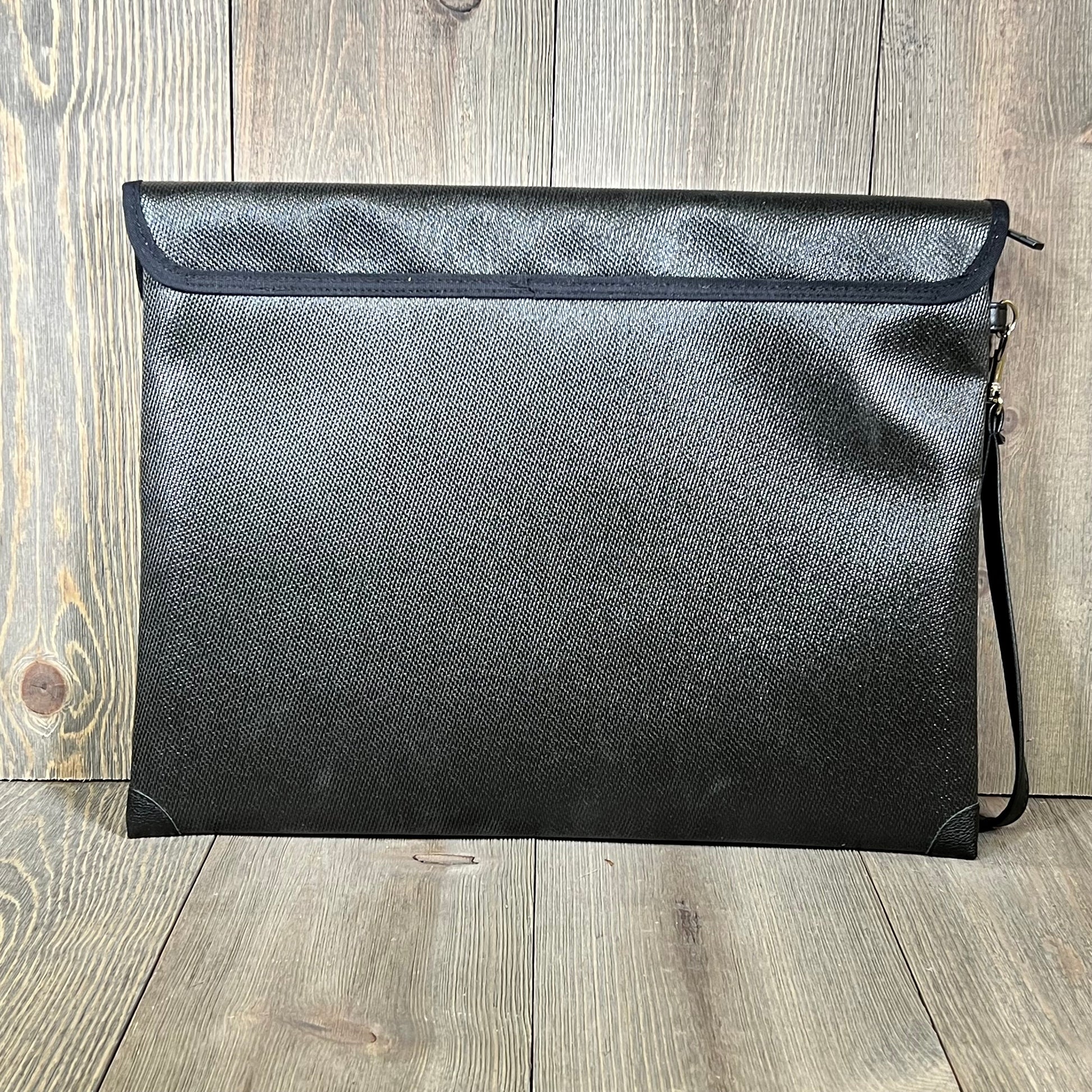 Fireproof document bag with lock, 9-layer heat insulation, black design, on a wooden surface.