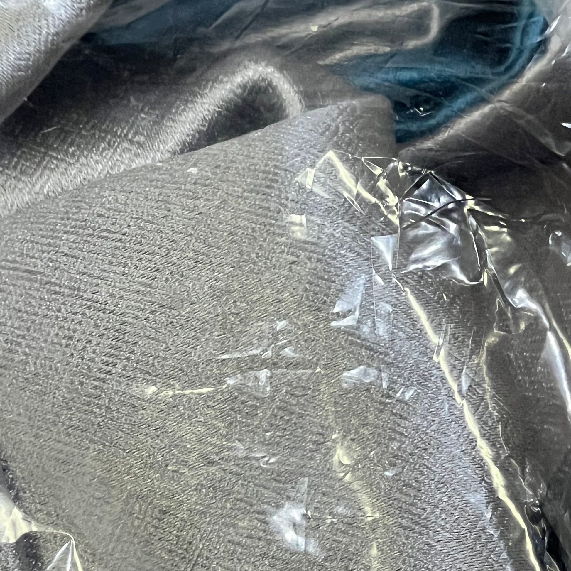 Close-up of grey and blue patchwork thermal curtains, showcasing texture and quality under protective packaging.