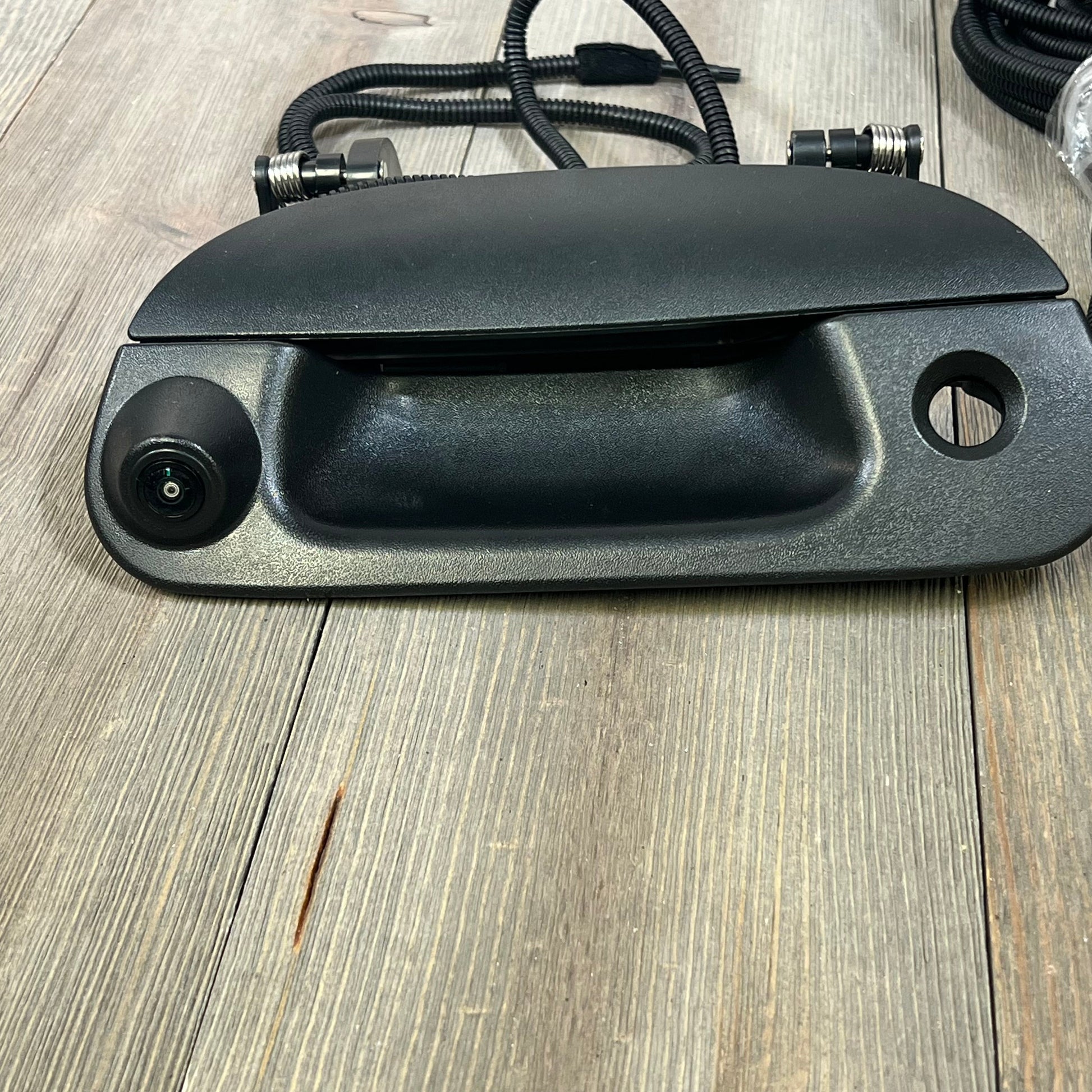 Backup camera tailgate handle for Ford F-150, F-250, Explorer; sleek design on wooden surface.