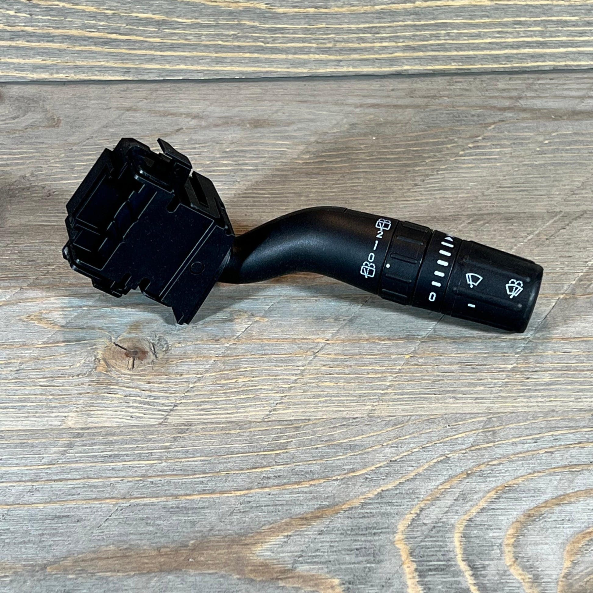 Black windshield wiper switch compatible with Ford Explorer, Edge, and Lincoln MKX on a wooden surface.
