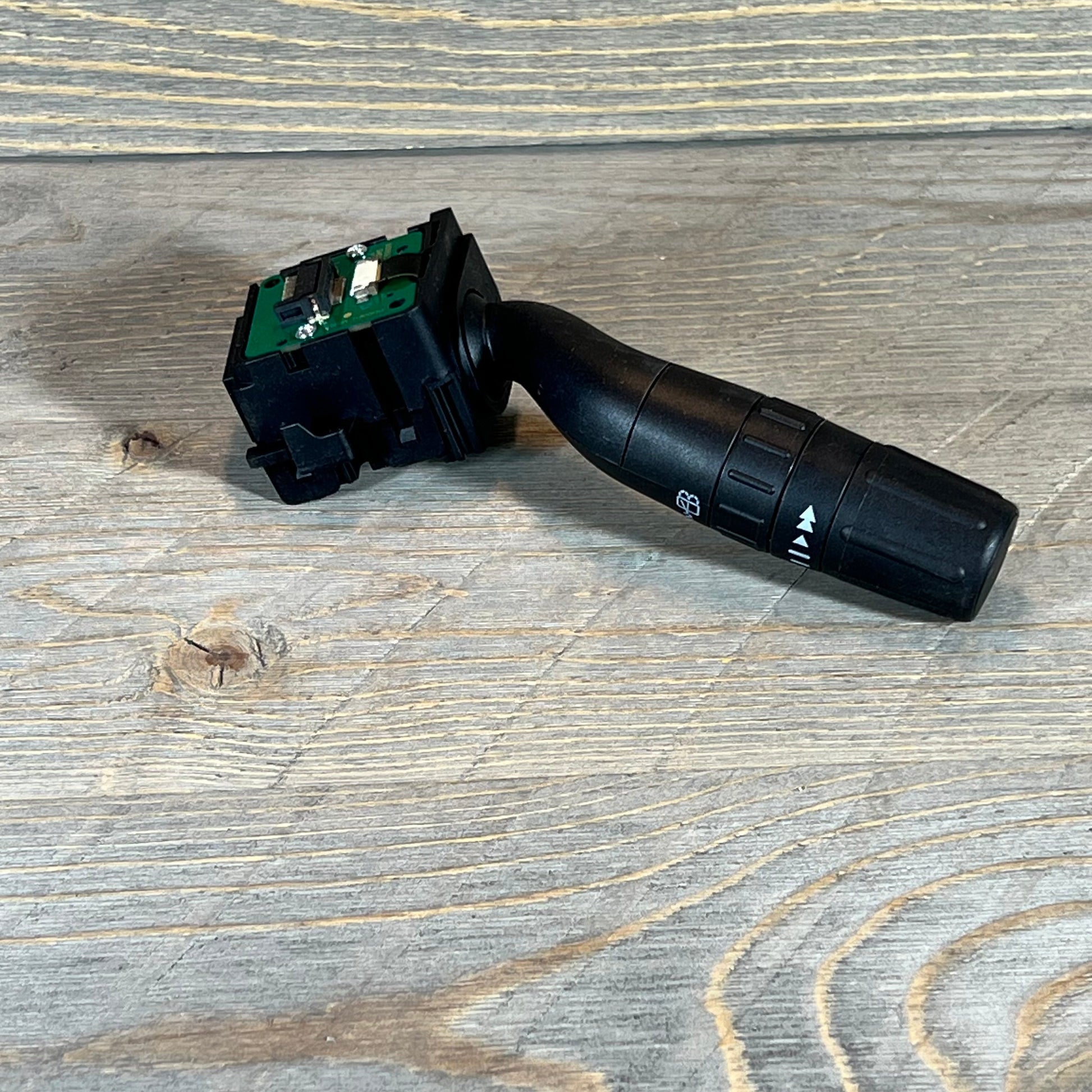 Black windshield wiper switch for Ford Explorer, Edge, Lincoln MKX on a wooden surface.