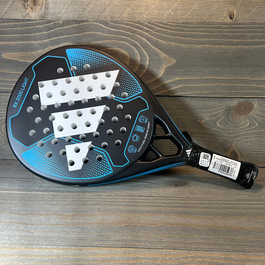 Blue Adidas RX 2000 Light padel racket with white accents on a wooden background.