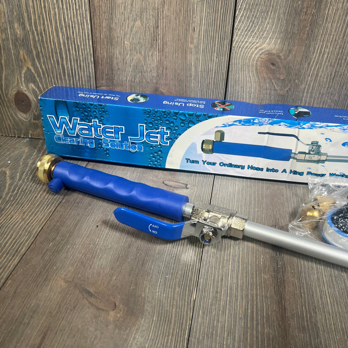 Water Jet cleaning solution kit with blue nozzle and brass hose connectors on wooden surface.