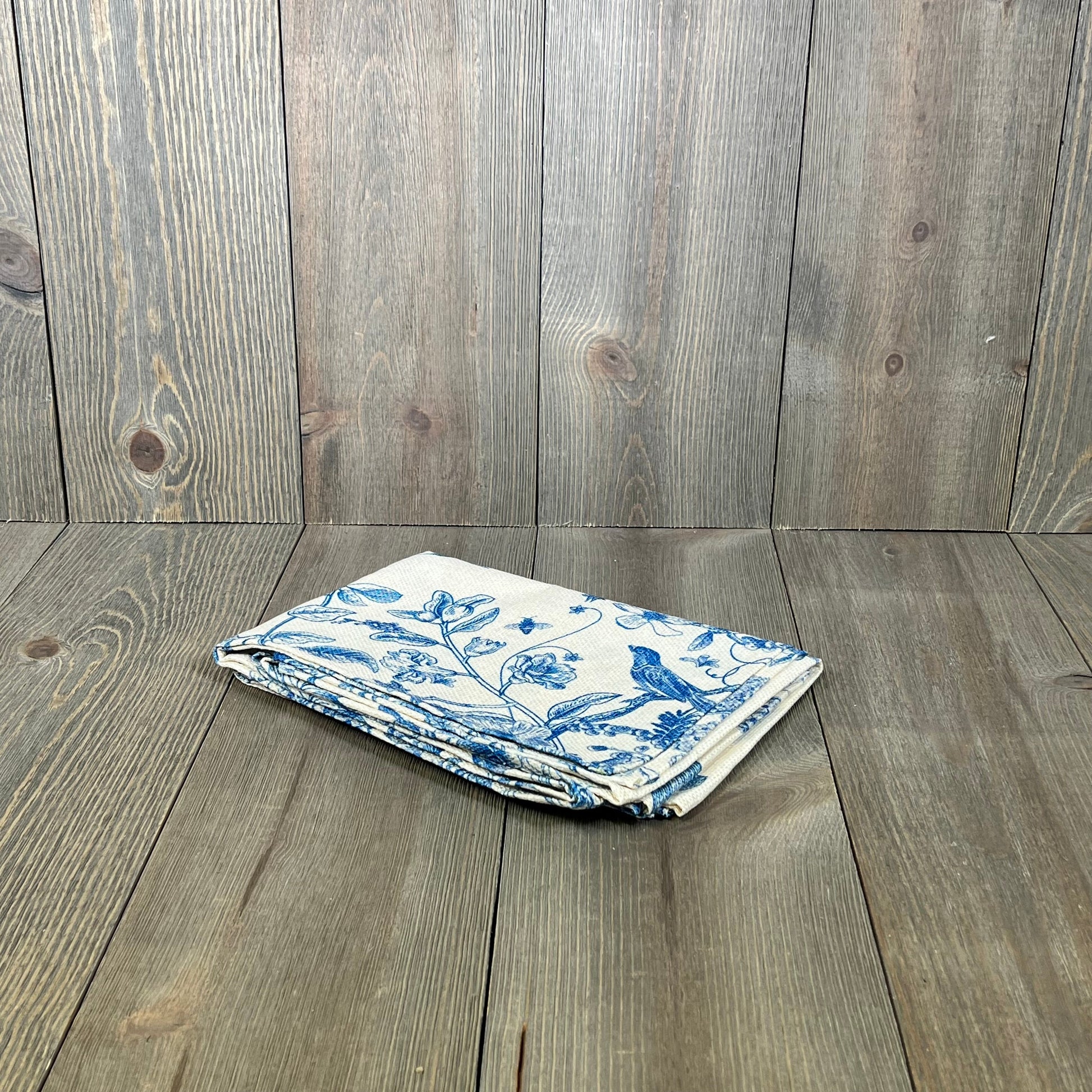 Folded Artoid Mode table runner with blue monochrome bird and flower design on wood background, ideal for seasonal decor.