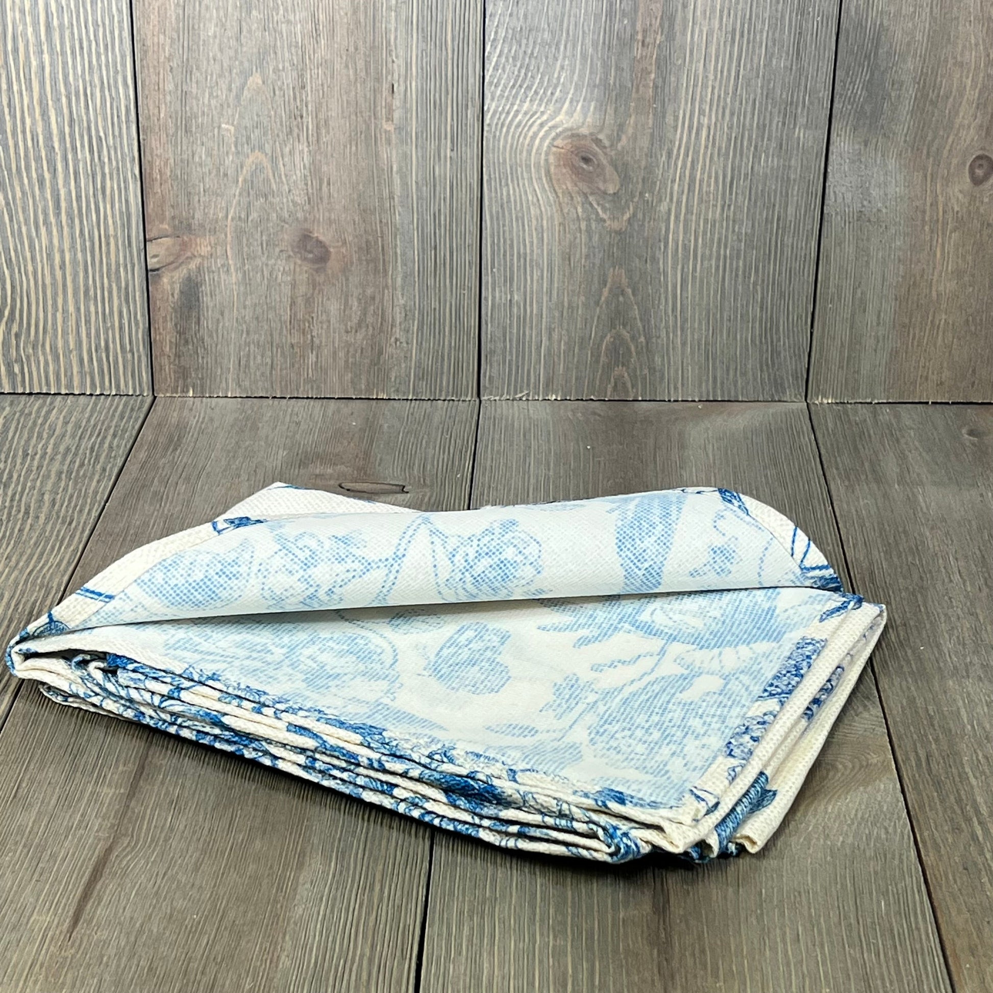 Folded blue and white floral table runner on a wooden surface, ideal for seasonal home and party decor.