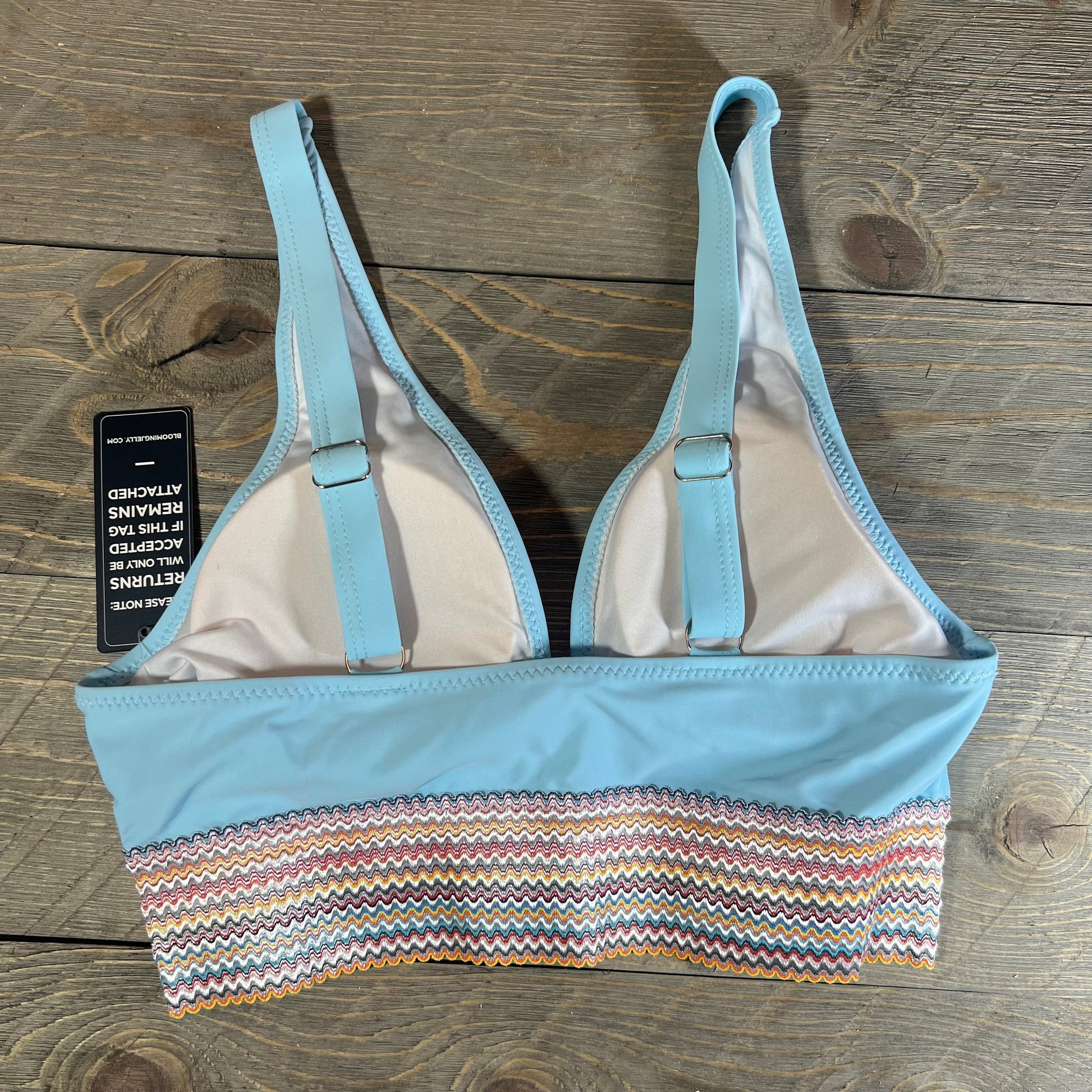 Blue high-waisted bikini top with colorful zigzag pattern on a wooden surface, featuring adjustable straps, size M.