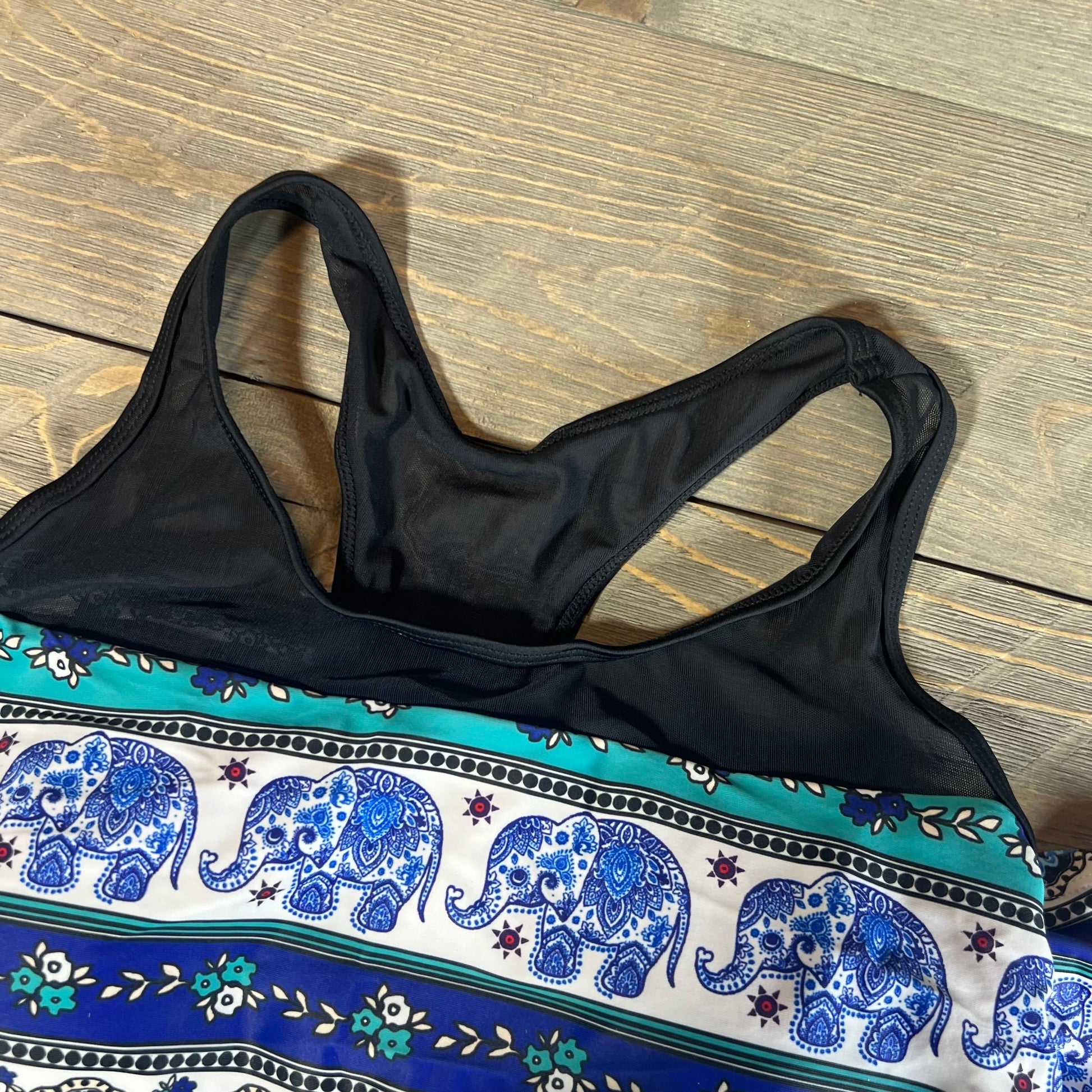 Blue mandala tankini swimsuit top with elephant print and black straps on a wooden background, size L.