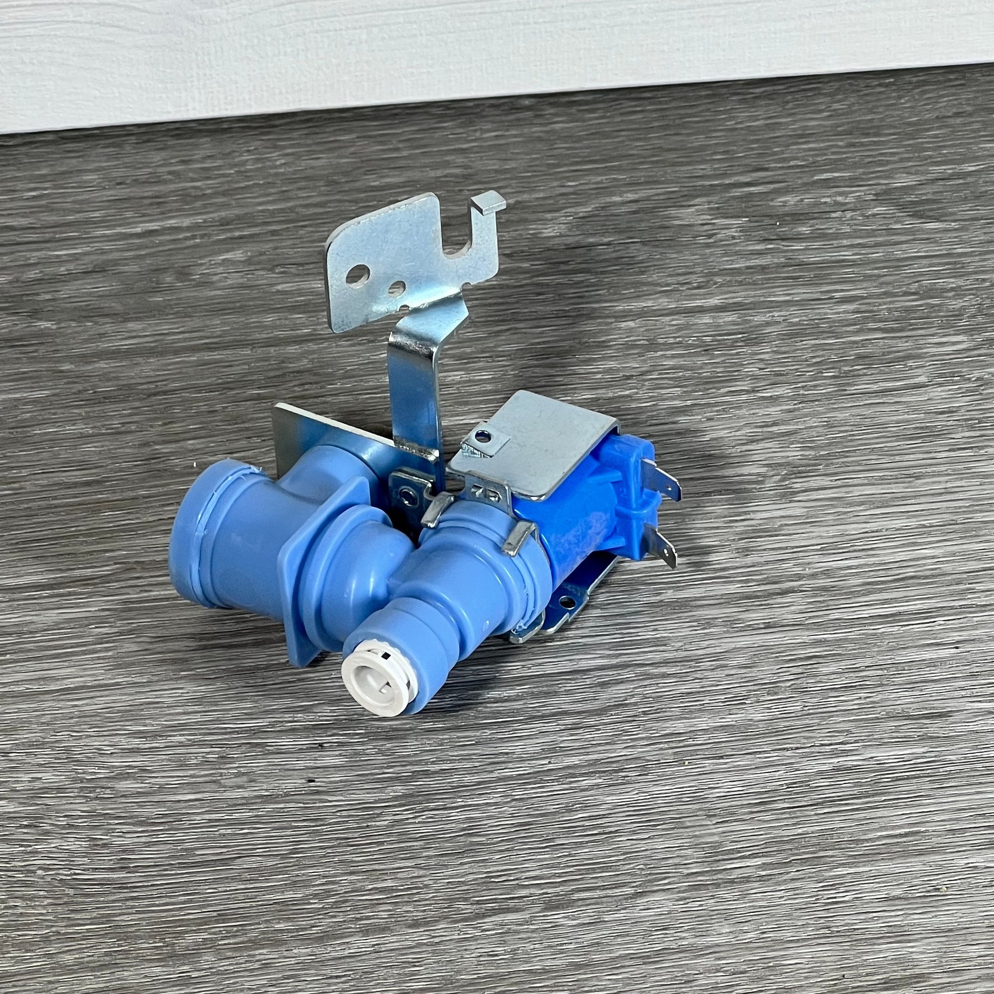 BlueStars MJX41178908 water inlet valve with dual ports for LG and Kenmore refrigerators on a wooden surface.